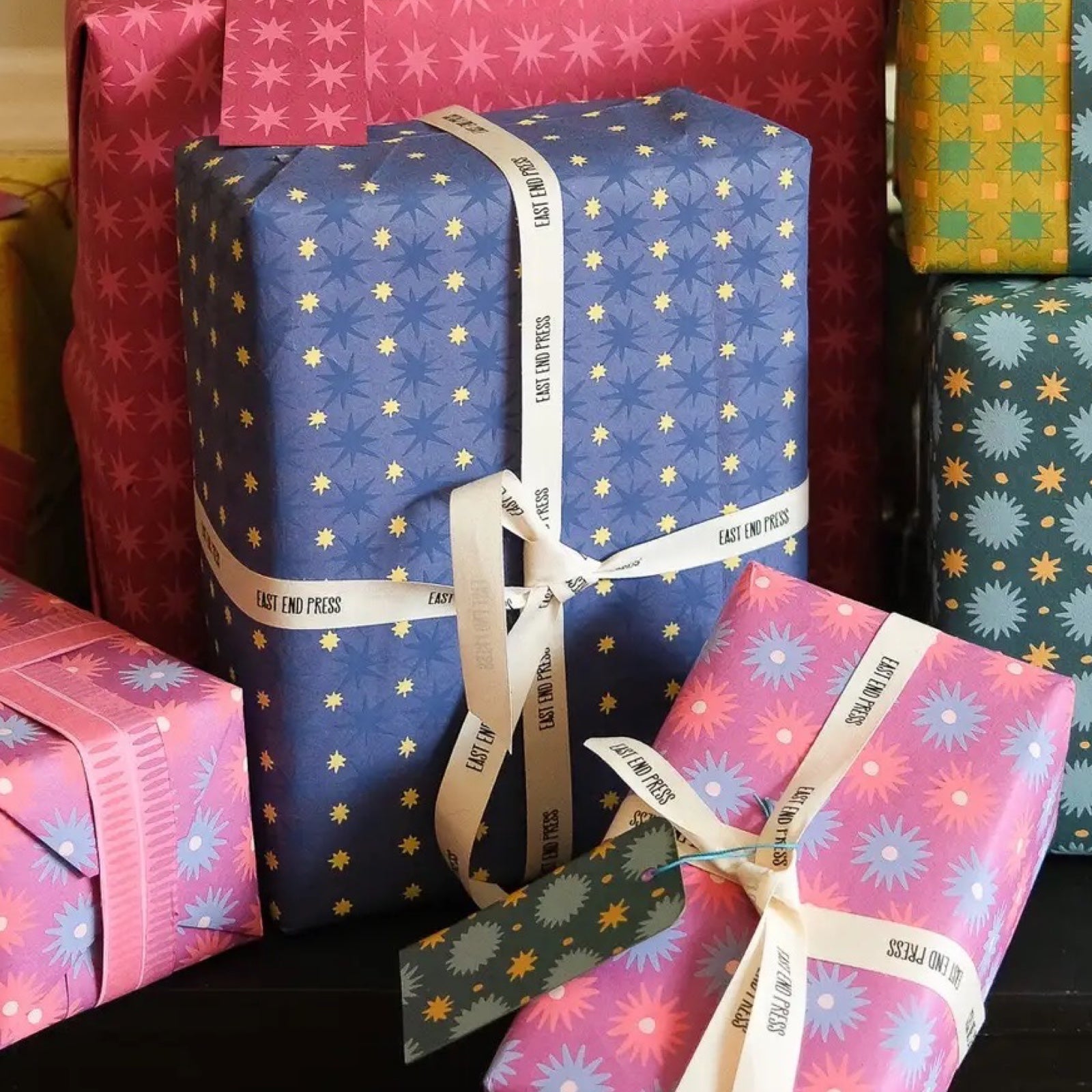 A present wrapped in wrapping paper with large dark blue stars and mini yellow stars against a midnight blue background