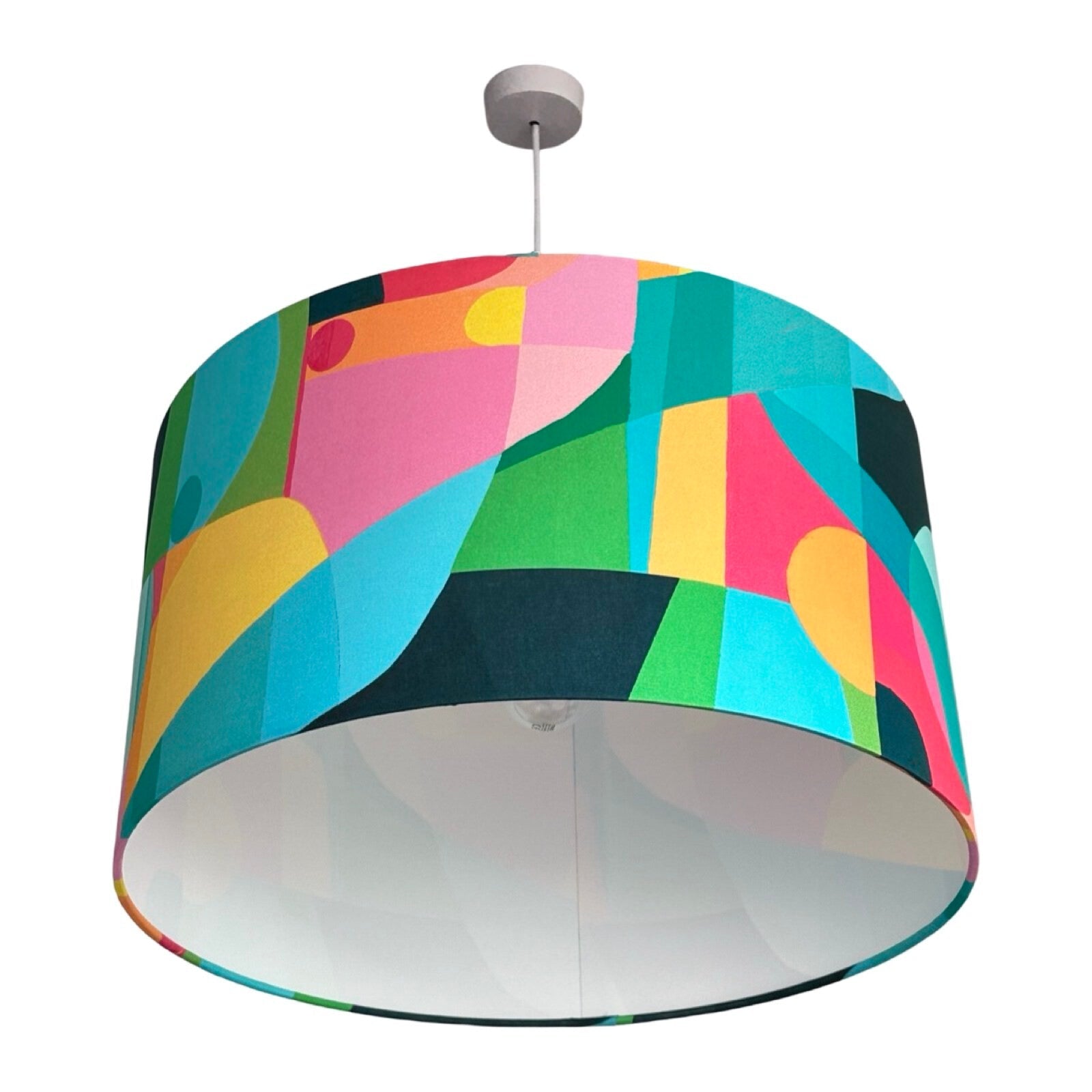 Drum lampshade covered in bright cotton fabric with abstract geometric shapes in turquoise, navy, pink, yellow and green