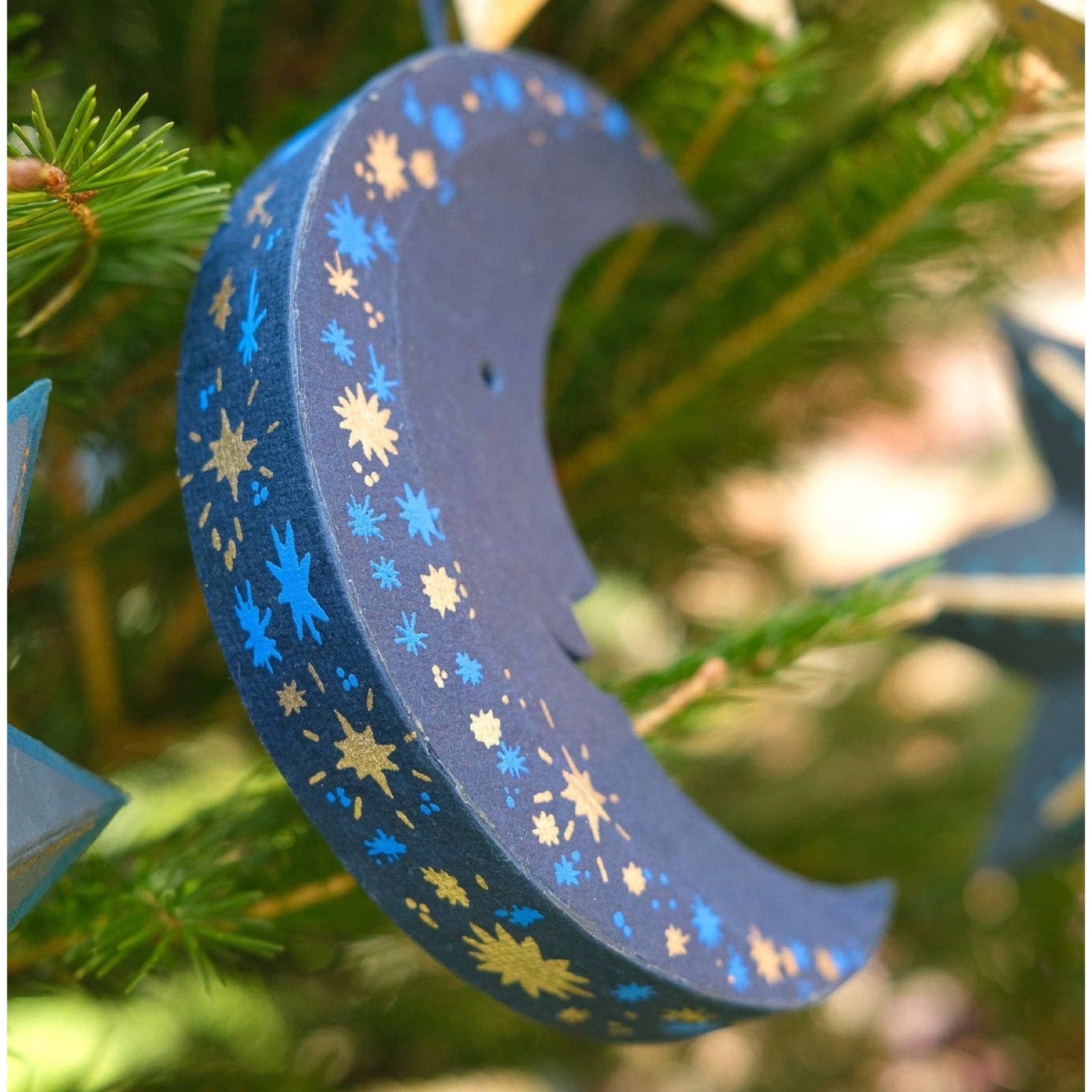 This gorgeous navy, blue and gold moon-shaped decoration has a matching 10cm cotton loop for hanging. Each moon decoration is made from 100% recycled paper, screen-printed by hand and moulded into a durable board decoration.