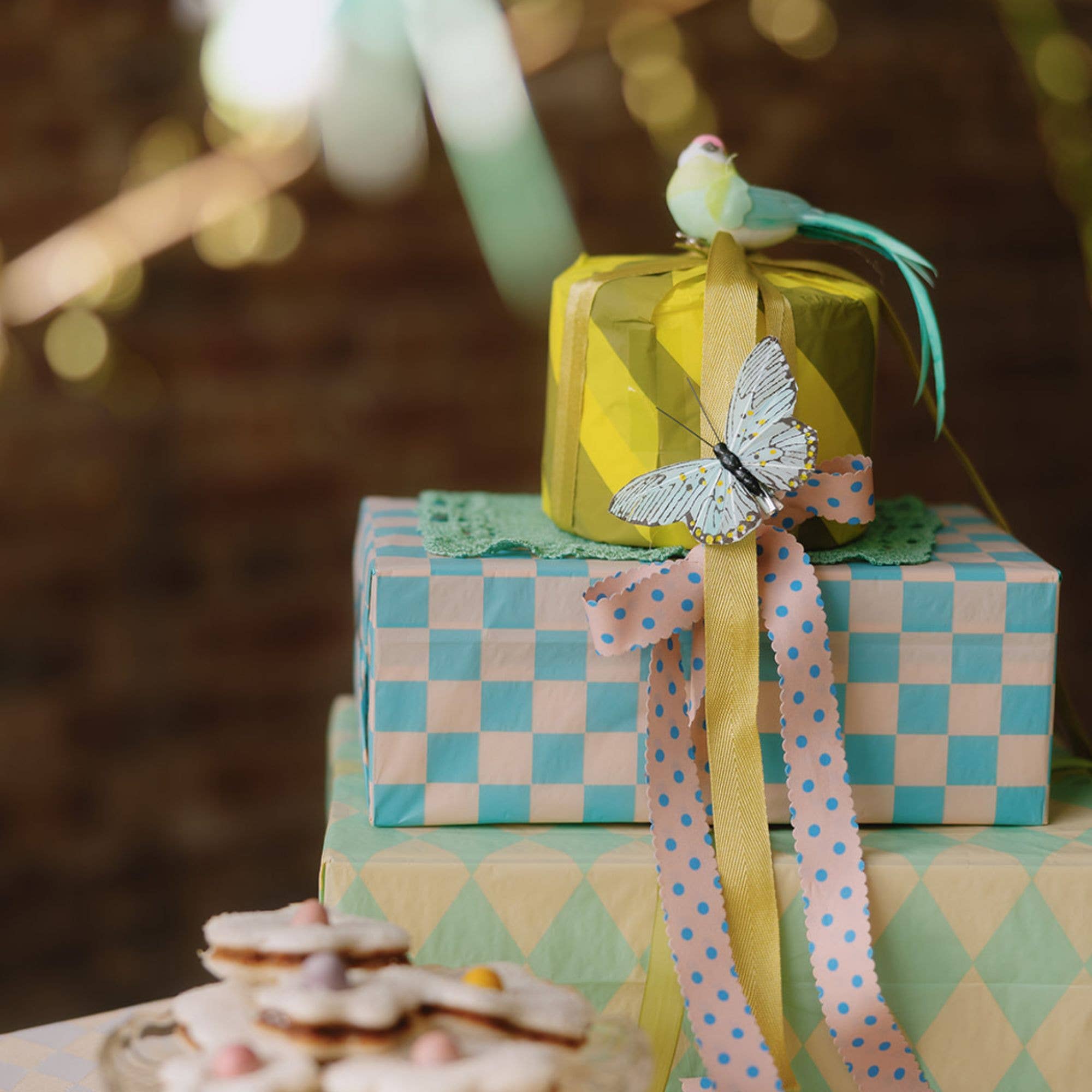 Decorative gift boxes wrapped in tissue paper with ribbons and a bird figurine on a blurred background.