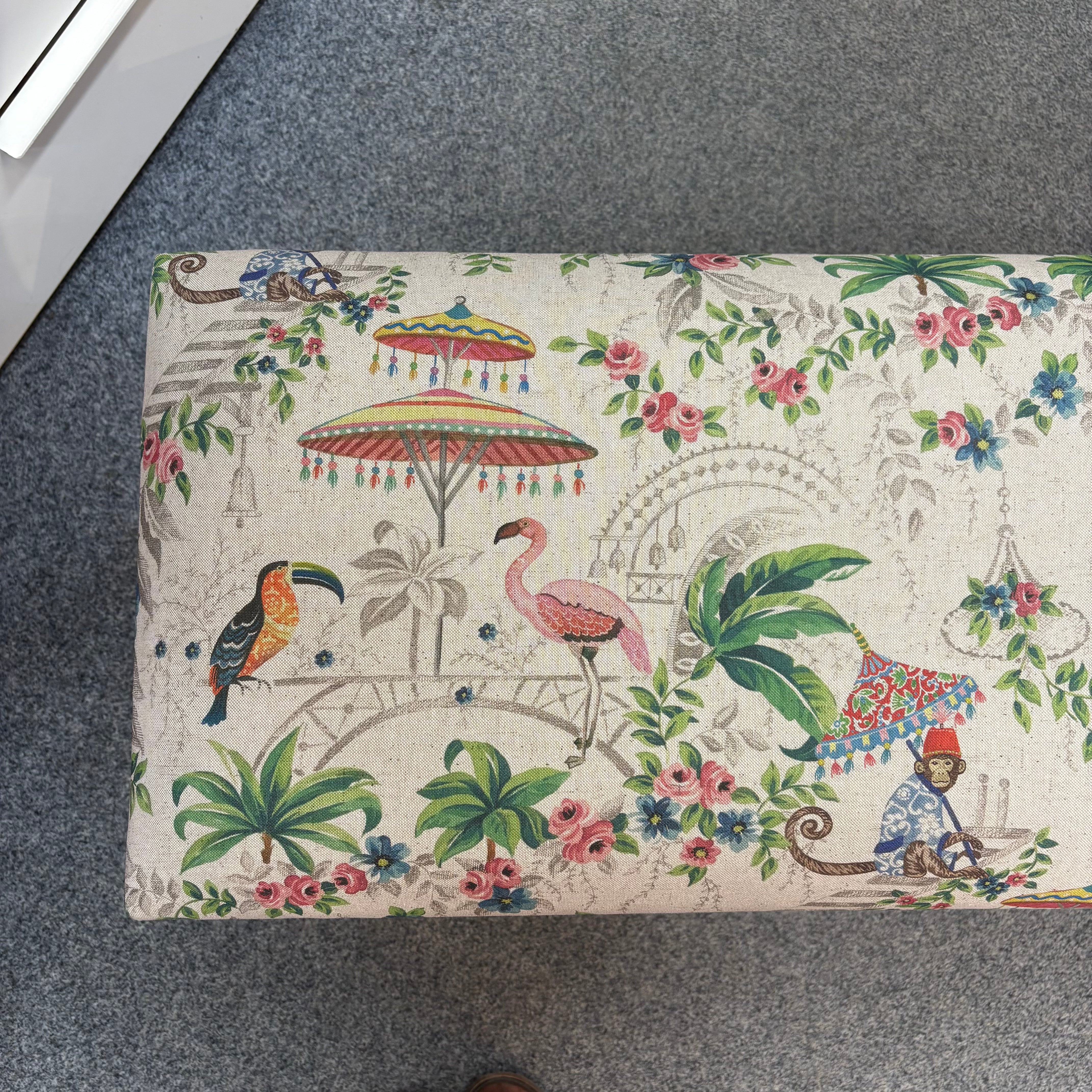Decorative bench with tropical design featuring birds, flowers, and a monkey on a grey surface.