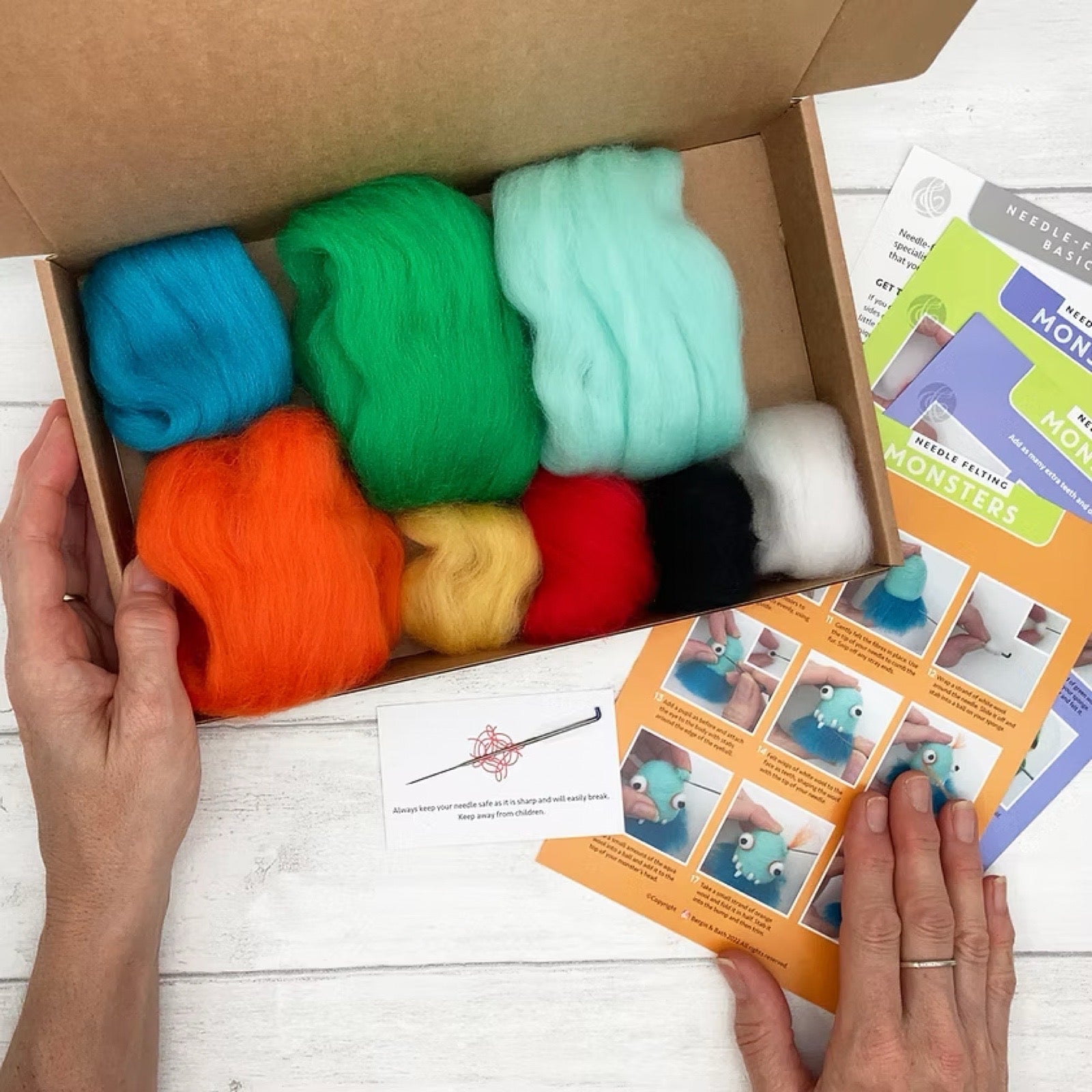 Box of colourful felting wool with instructions on a wooden surface/