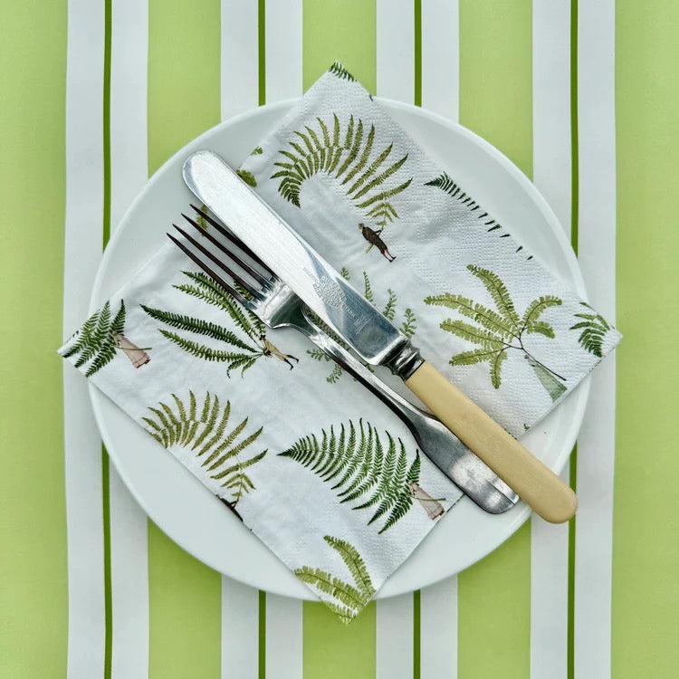 Napkin with fern pattern on a plate with cutlery against a striped background.