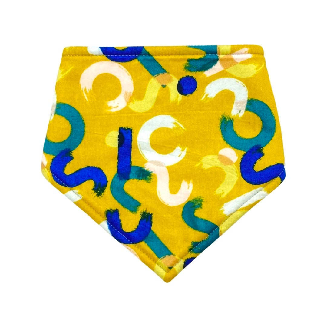 A yellow bandana bib with mustard brush strokes pattern designed for babies.