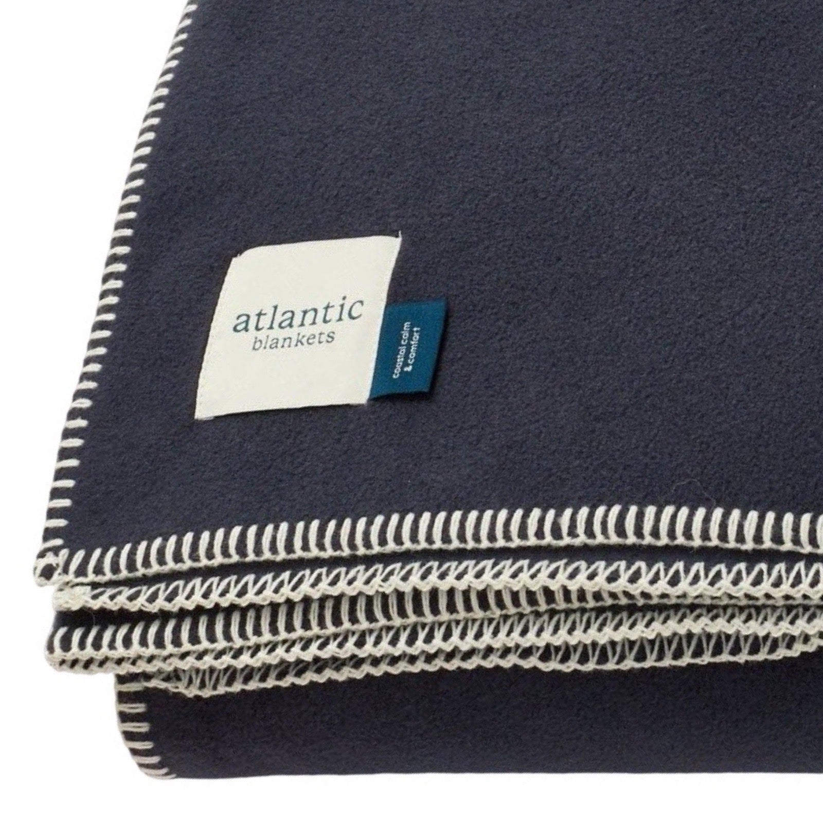 Navy blanket with white stitching and Atlantic Blankets label on a white background.