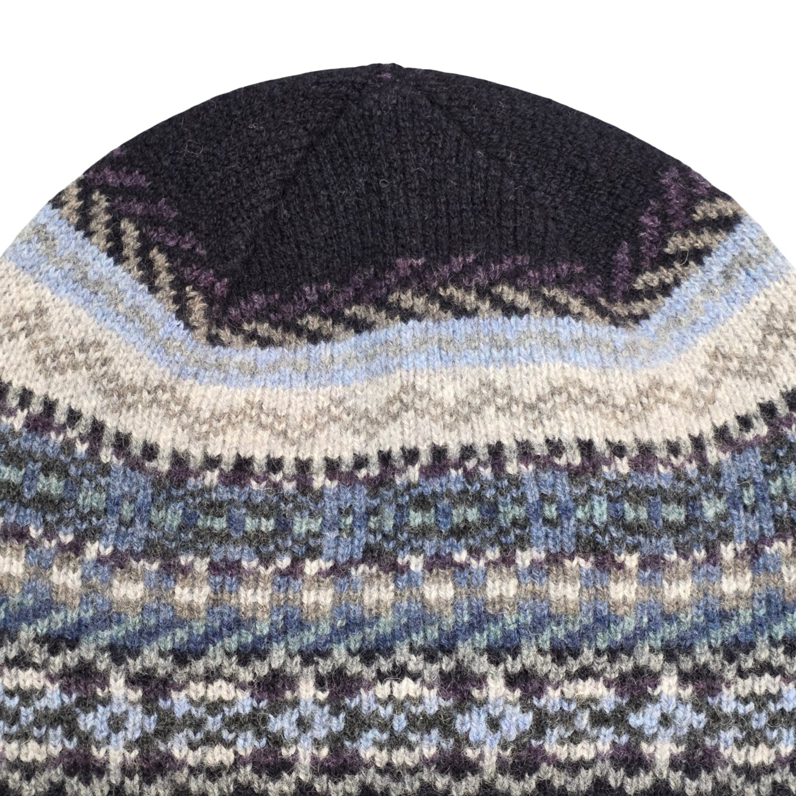 Close-up of a knitted hat with a patterned design on a white background.