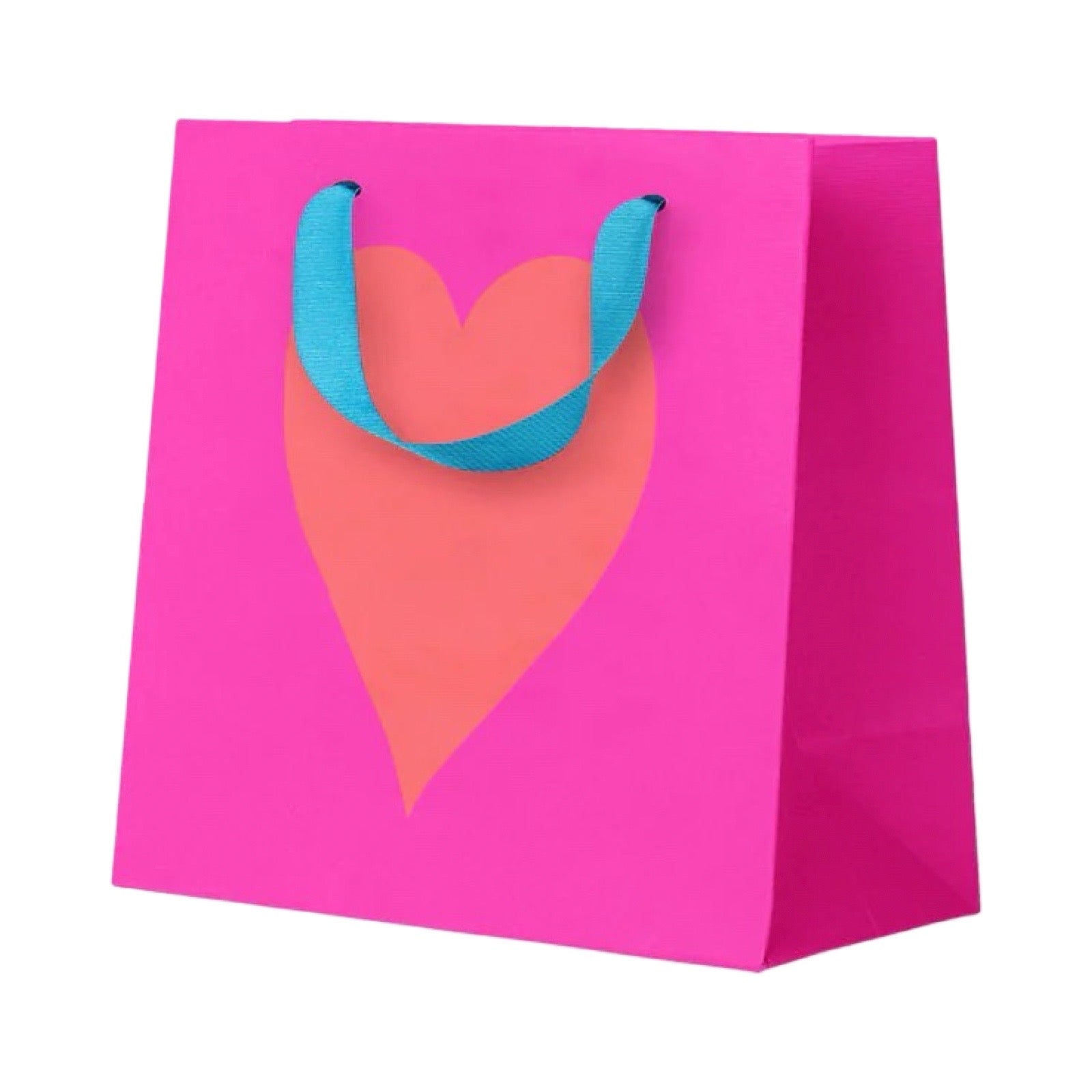 A bright pink paper gift bag with a large coral-pink heart printed on the front and twisted blue ribbon handles, shown on a plain white background.