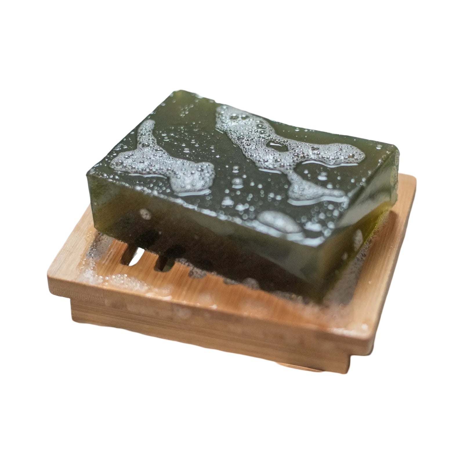 A bar of black nettle soap sitting on a wooden soap dish.