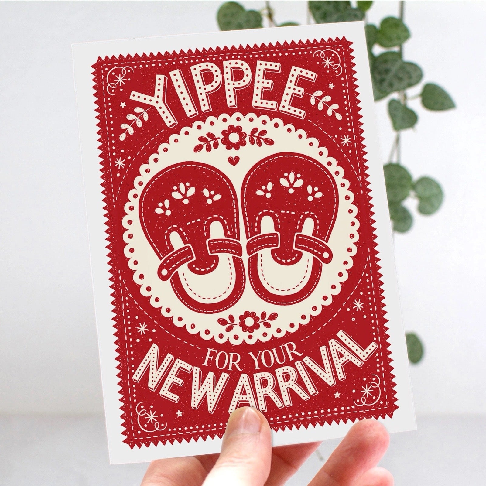 Red and white baby card with 'Yippee for your new arrival' text and shoes design.