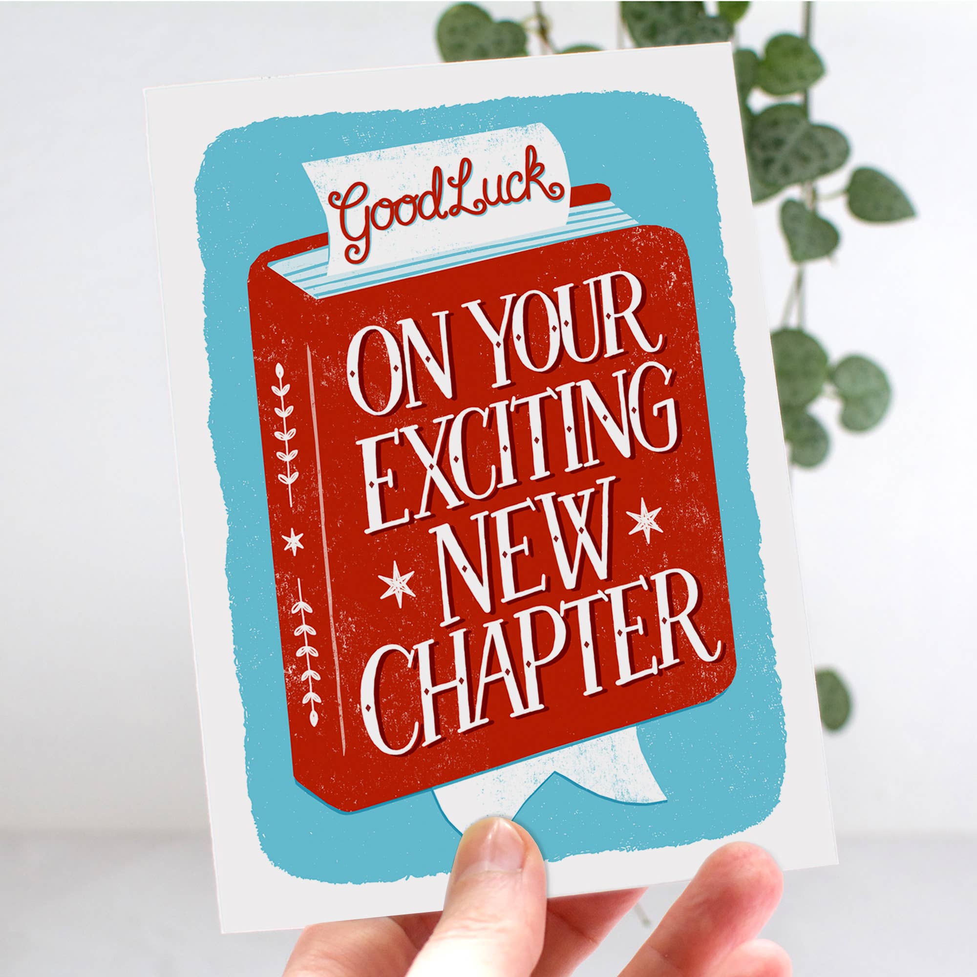 Greeting card with 'Good Luck on Your Exciting New Chapter' text held by a hand.
