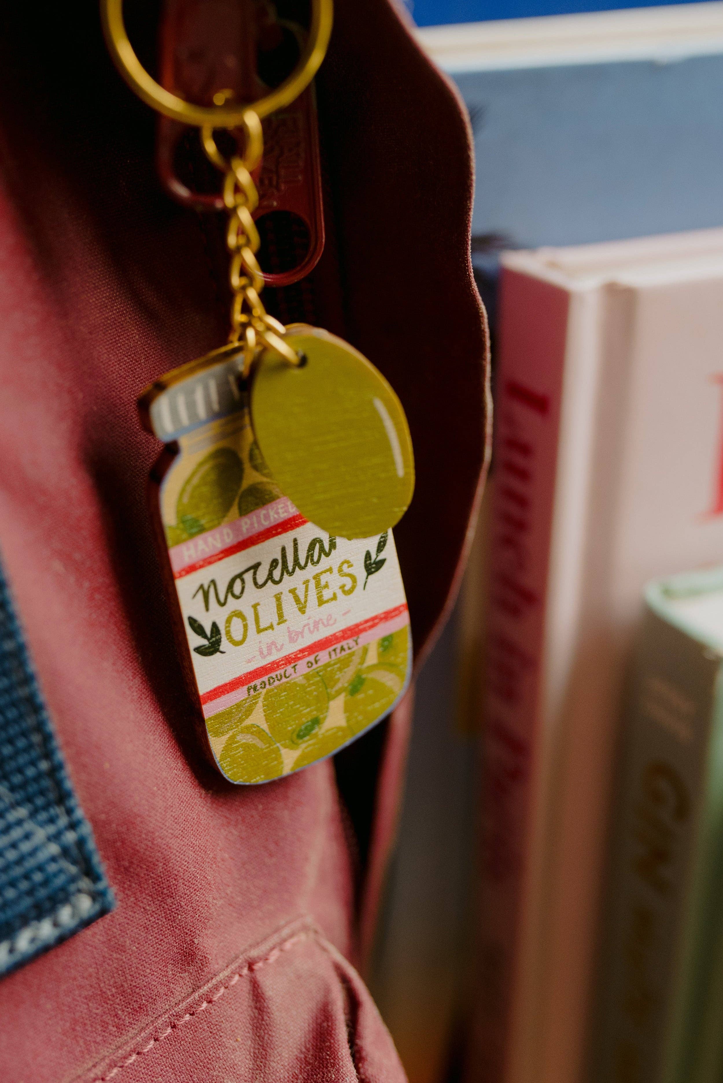 Keychain shaped like a bottle of olives attached to a jacket.