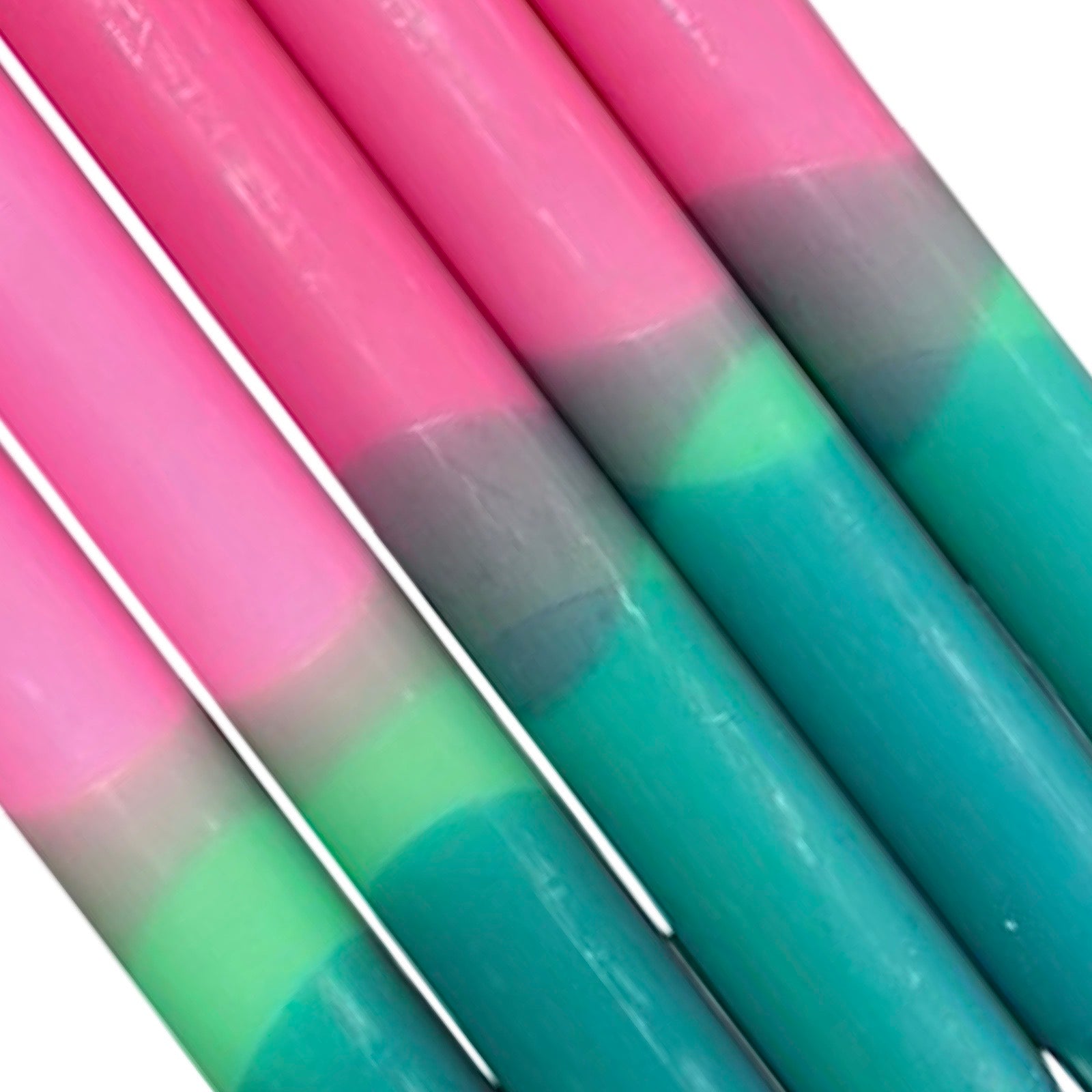 A row of five handmade dinner candles with a green base, a lighter green centre, and a pink top.