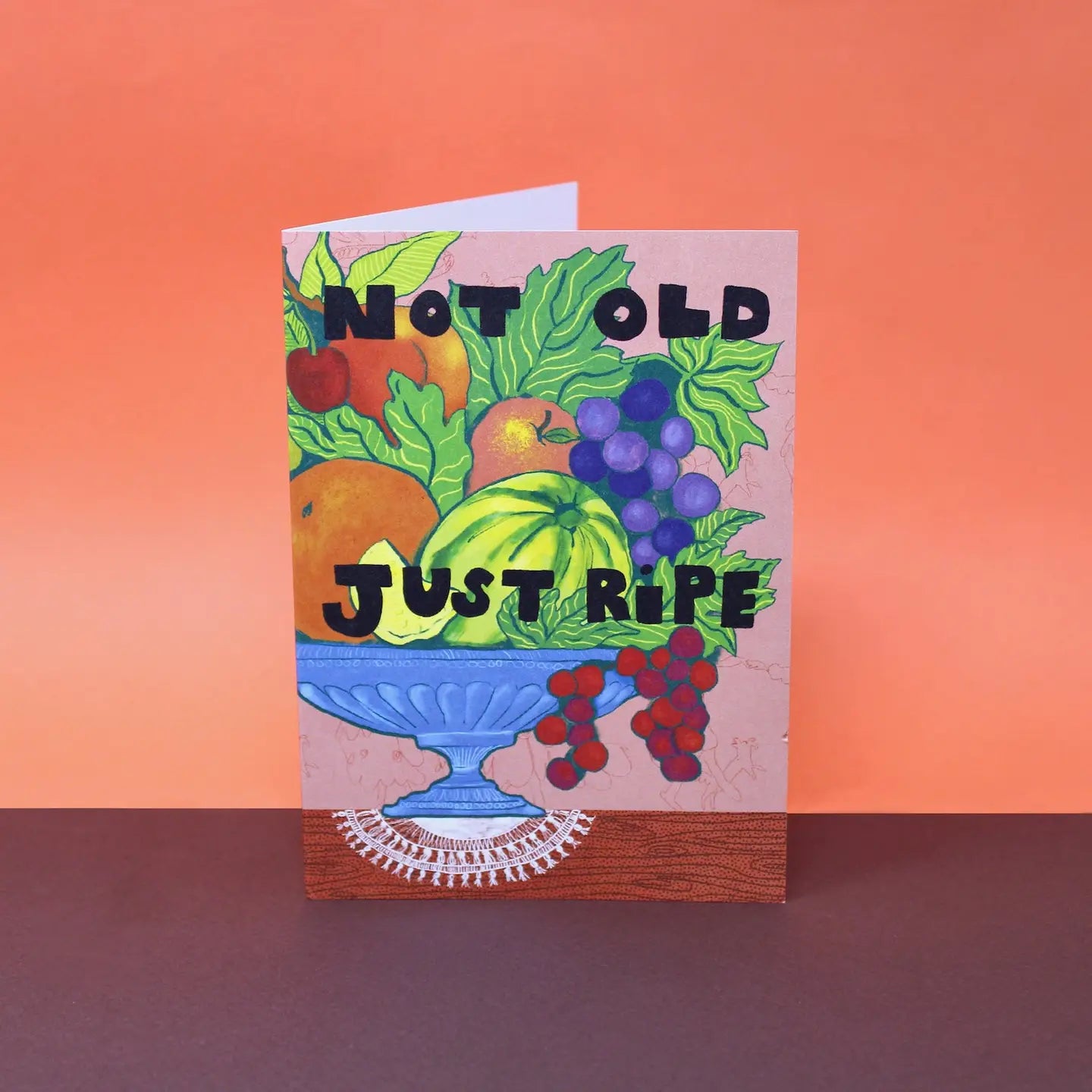 Card with fruit illustration and text 'Not Old Just Ripe' on an orange background.