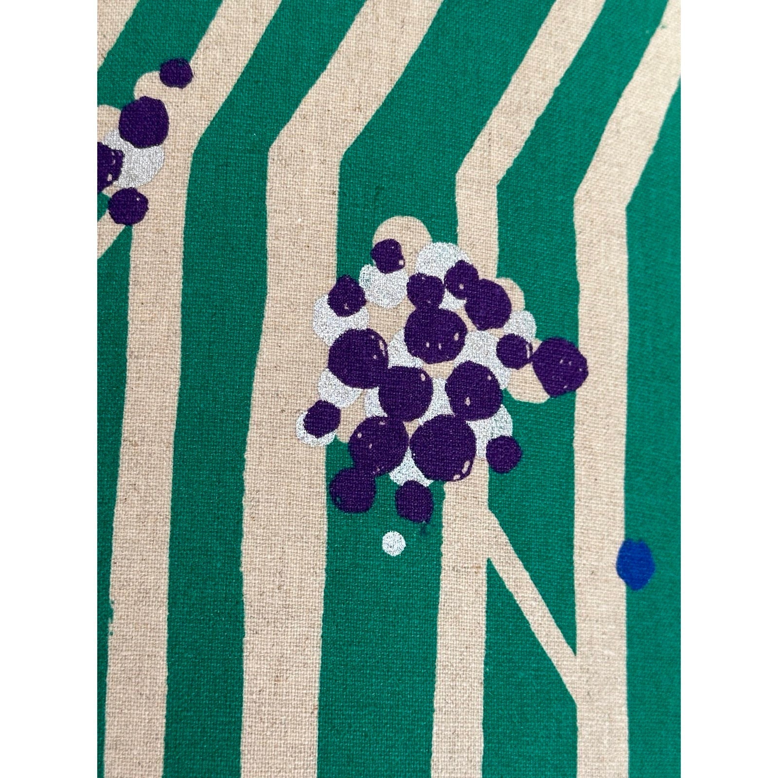 Fabric featuring purple and silver clusters of nuts and white tree branches against a green background