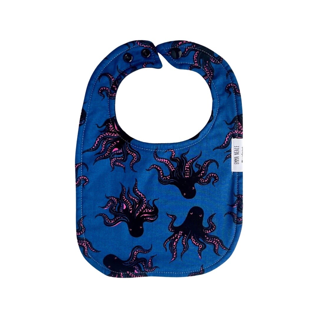 Traditional style bib in octopus fabric with adjustable neck fasteners.
