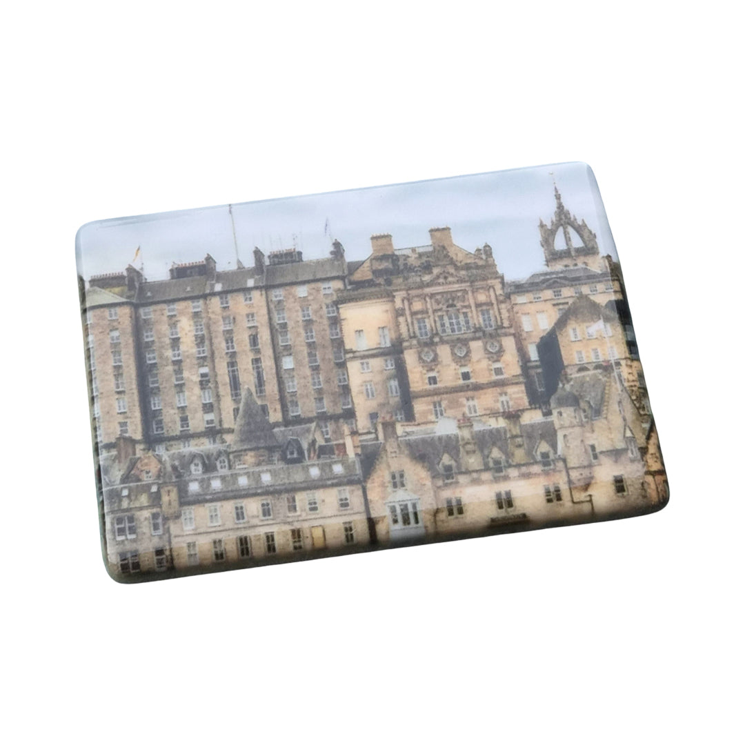 A ceramic magnet showing a picture of Edinburgh.