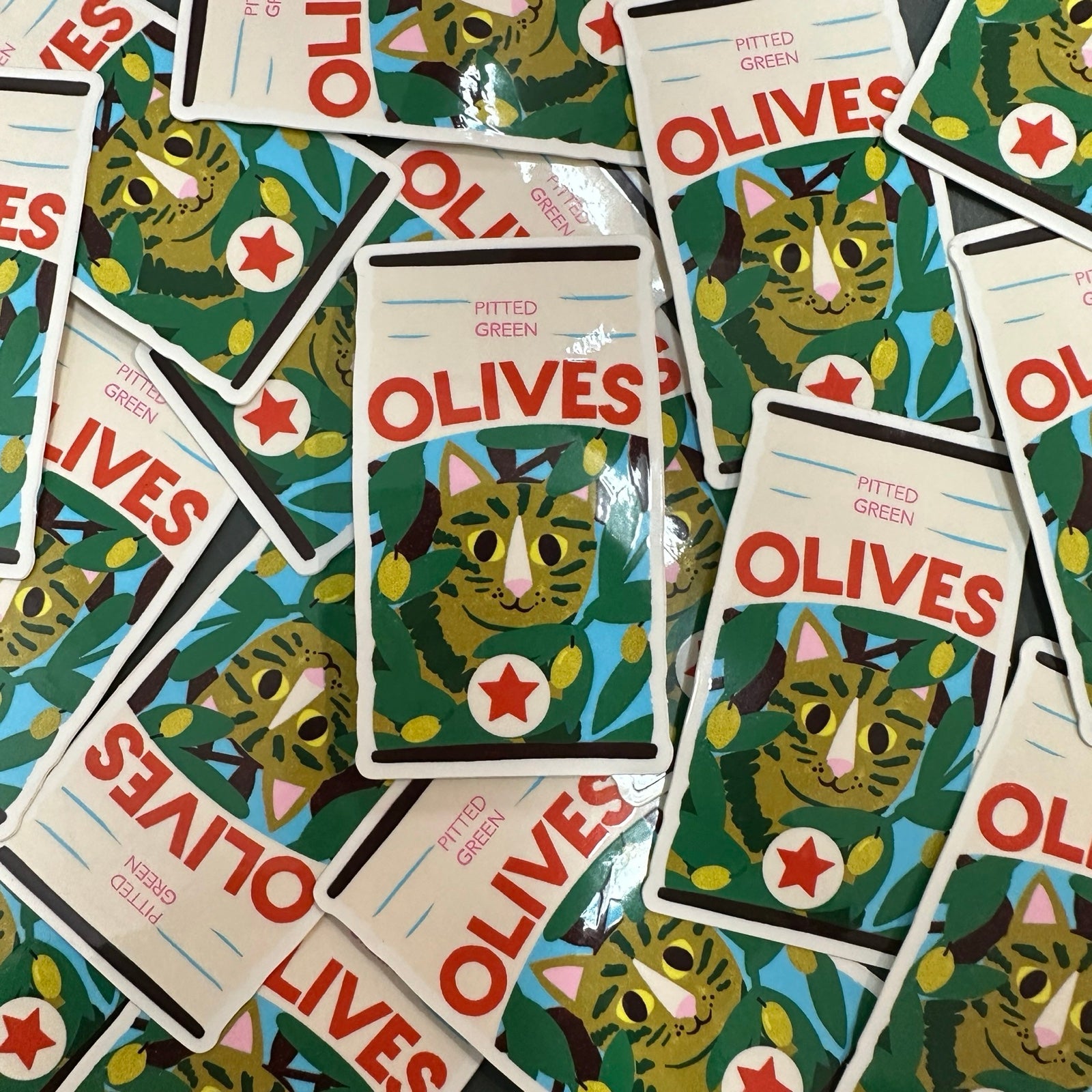Packaging of olives with cat illustrations on a green background.