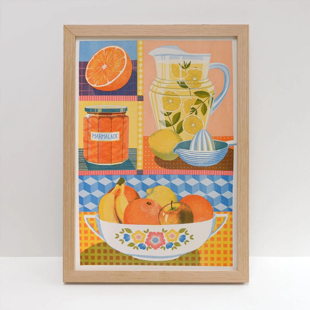 Framed artwork including a pitcher, lemons, oranges, and a bowl of fruit on a checkered tablecloth.