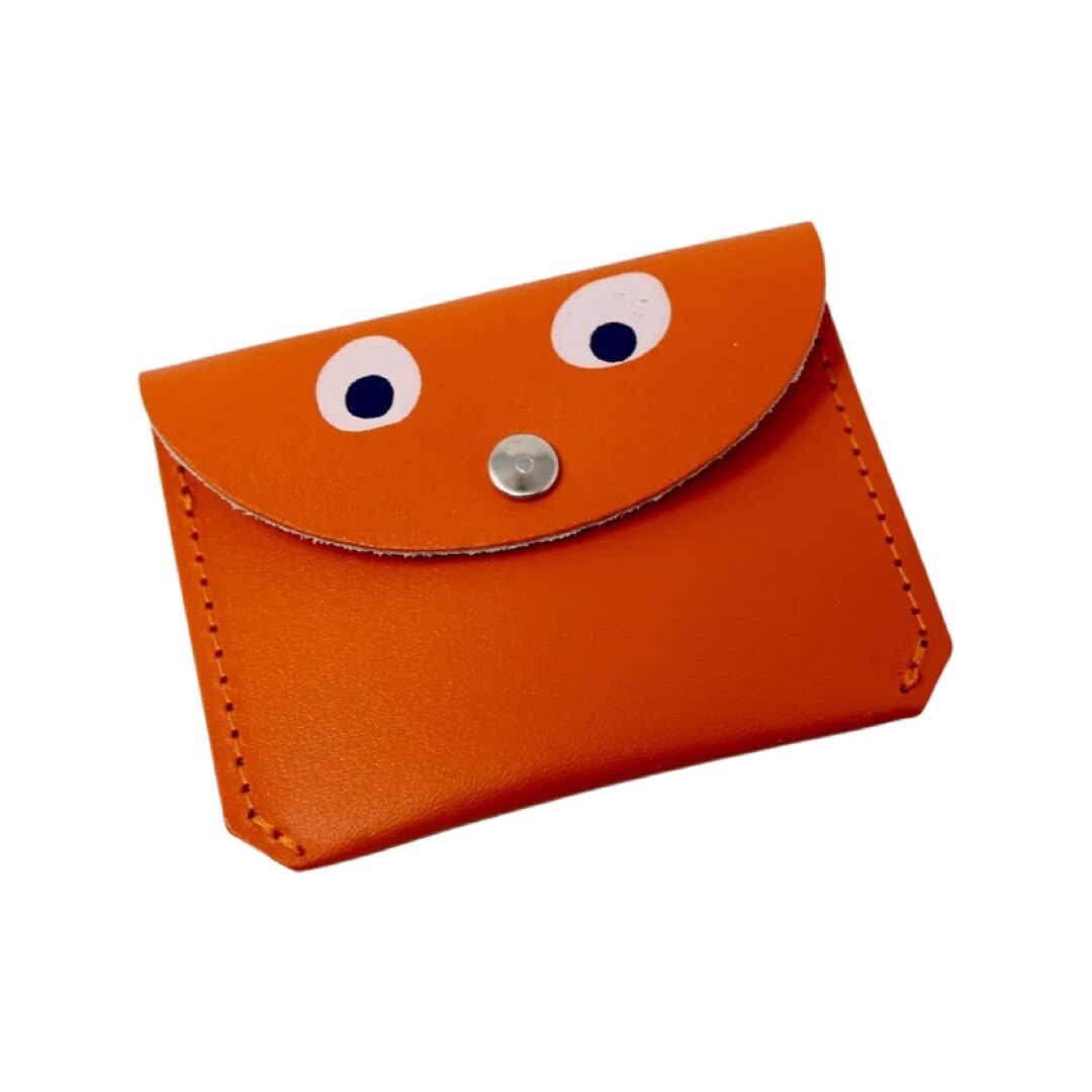 An orange leather coin purse with googly eyes and a gold fastening in the centre.
