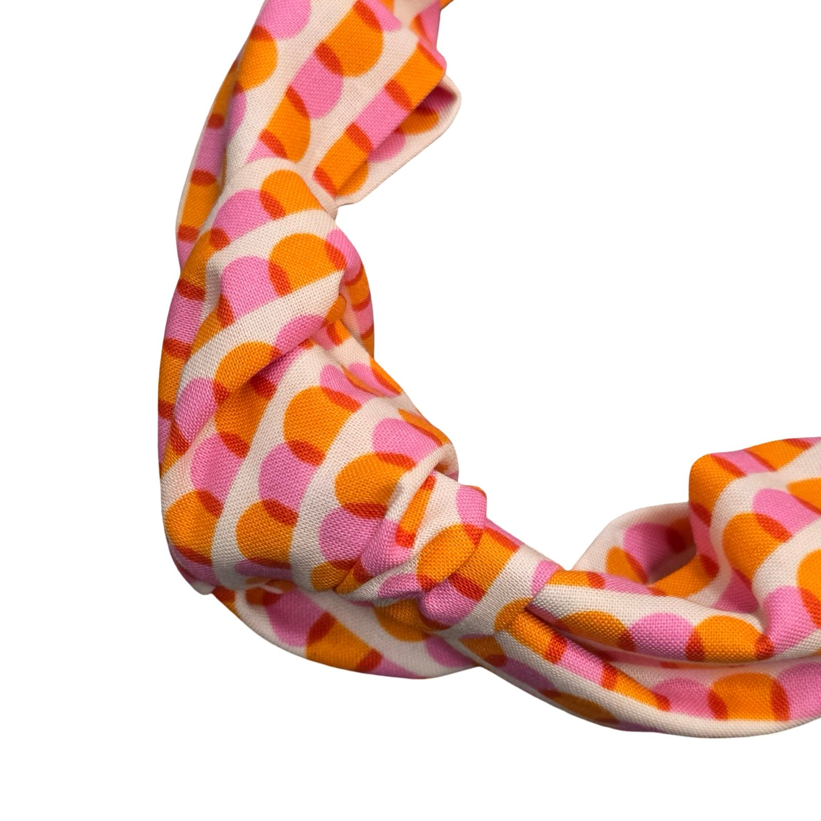 This handmade floral top-knot Alice band is made from 100% cotton fabric with an orange and pink scalloped pattern.