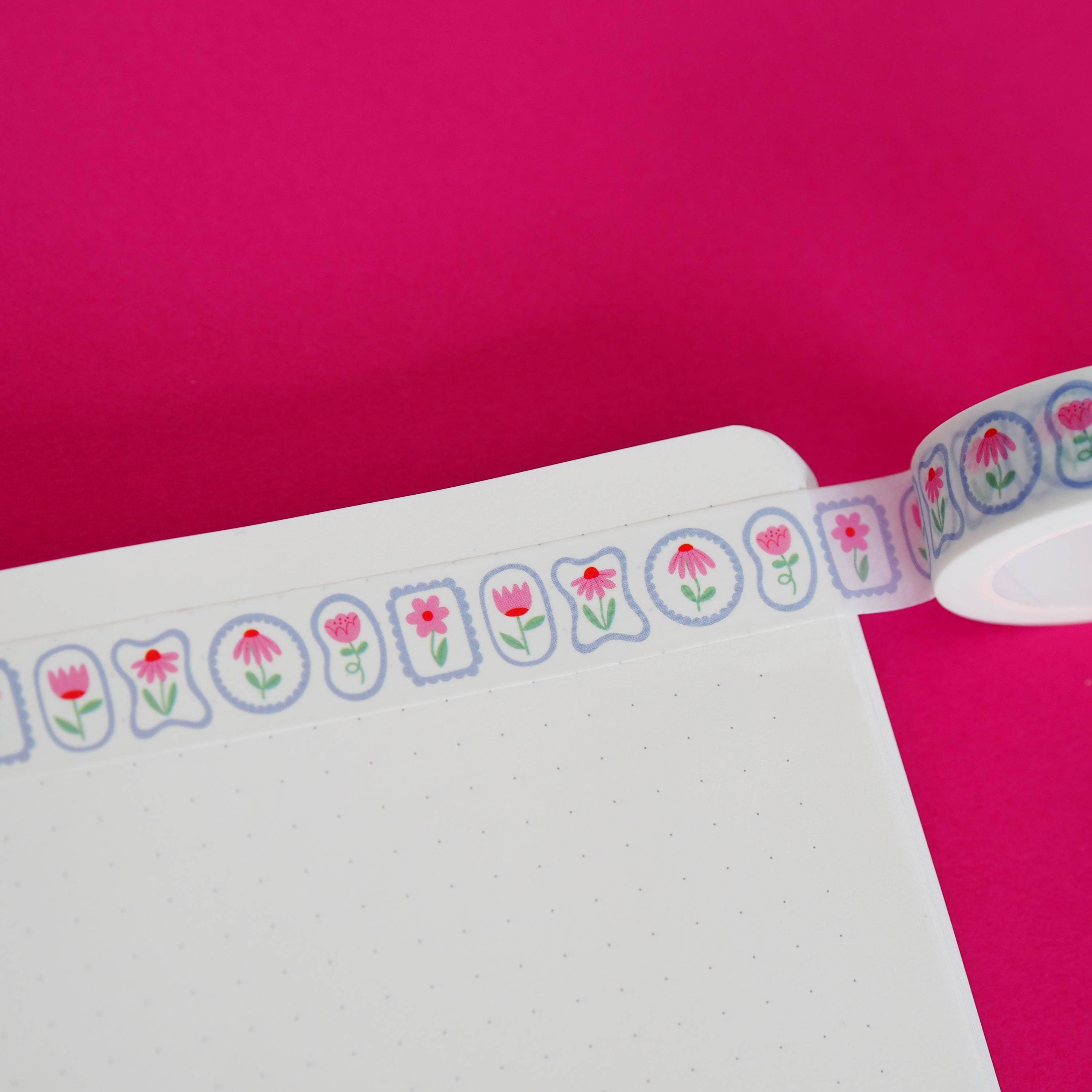 Floral pink washi tape on white paper on a pink background.
