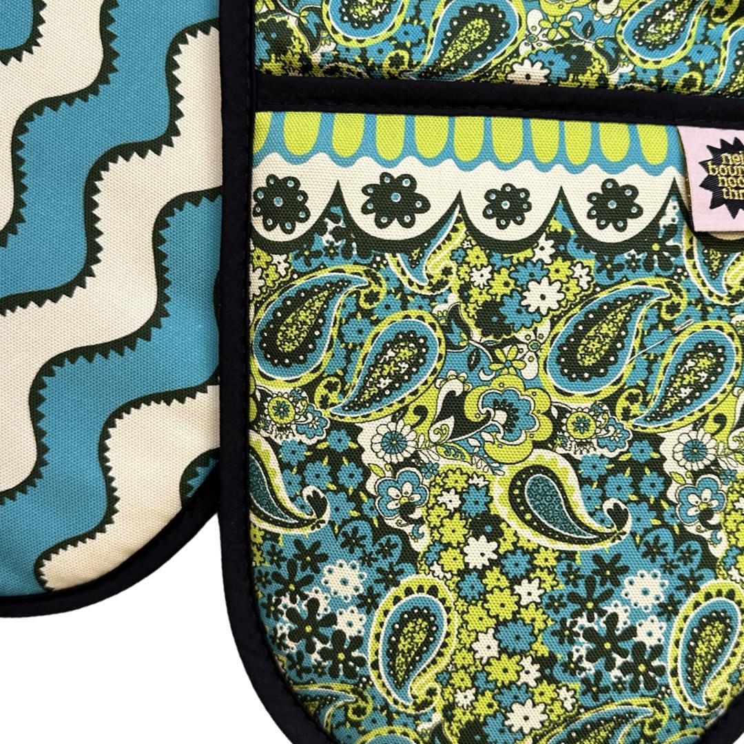 Close up of green and blue paisley pattern design oven gloves with turquoise and cream wiggly stripes on the reverse.