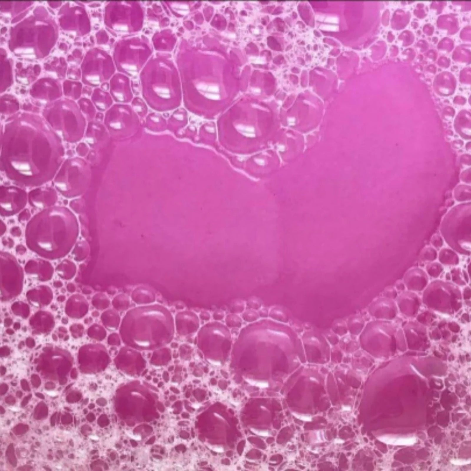 Pink bath water with bubbles.