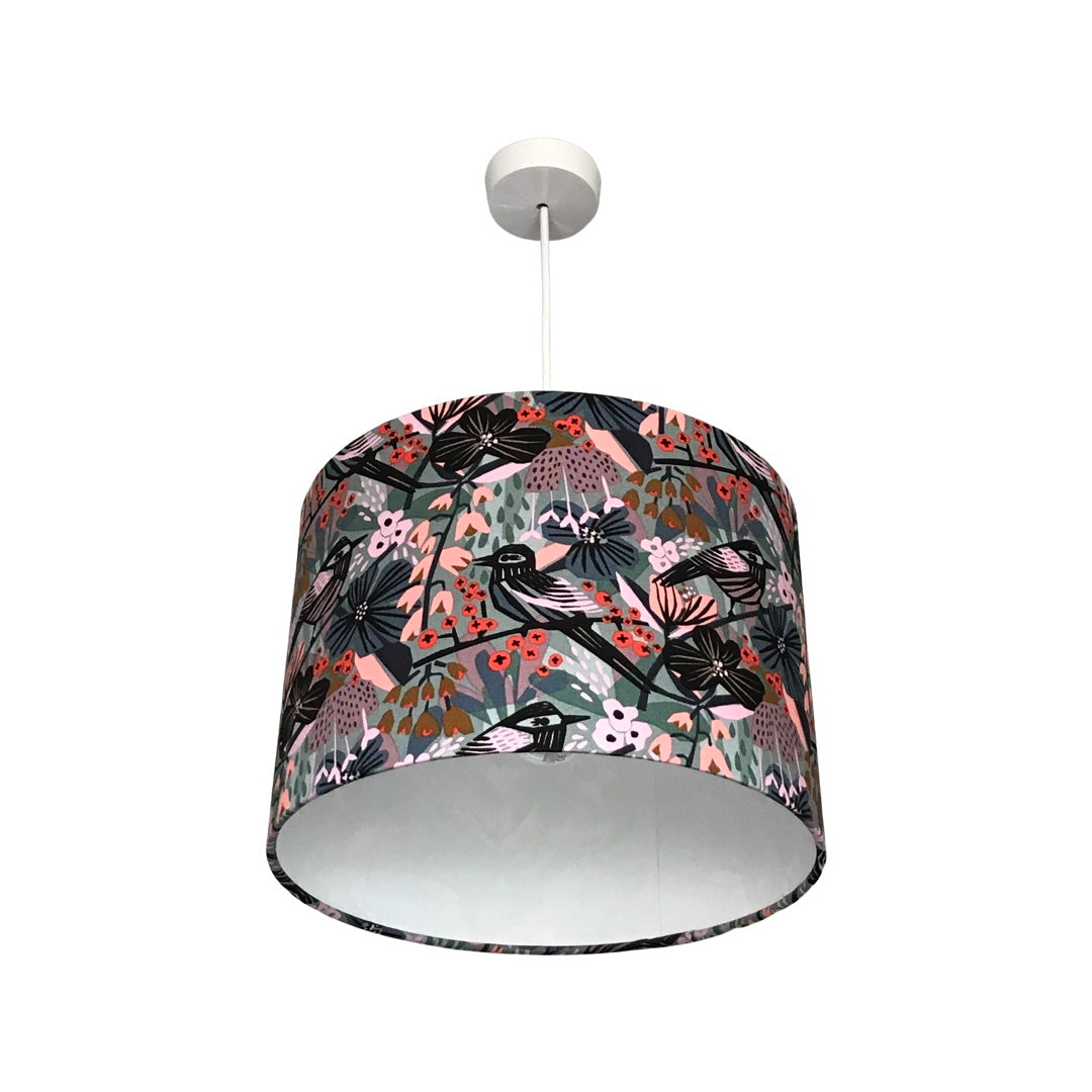 Drum lampshade covered in canvas fabric with black birds in a pastel pink, blue and grey floral background.