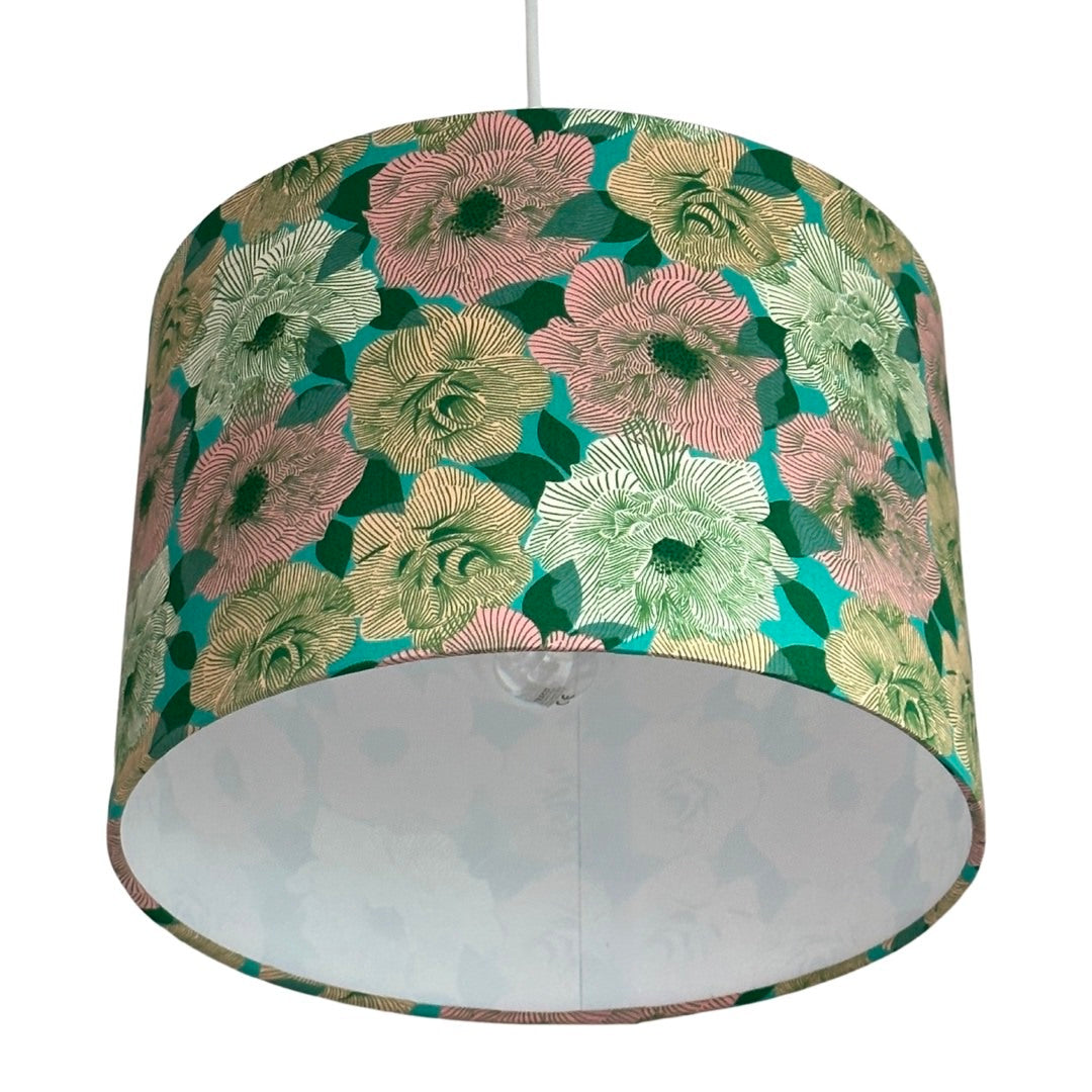 Close up of a drum lampshade featuring a green background with white, pink and cream roses
