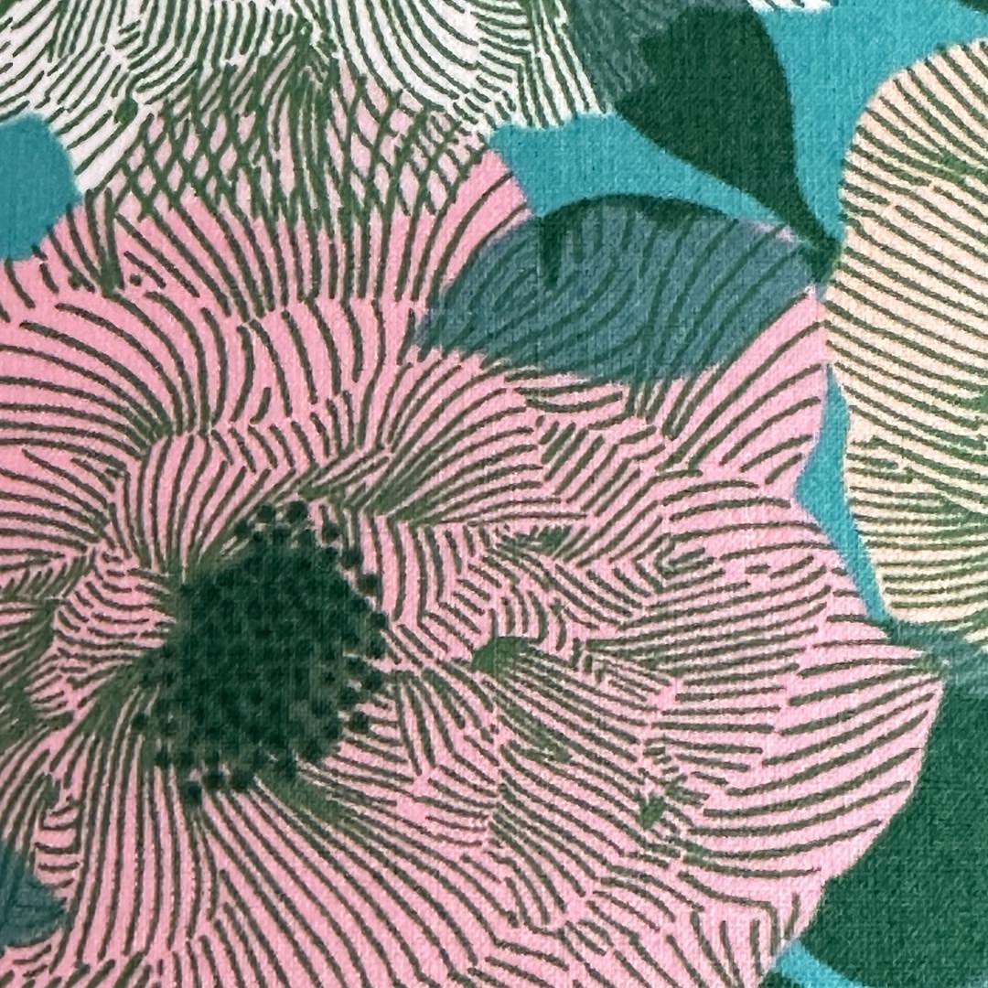 Close up of cotton fabric featuring a green background with white, pink and cream roses