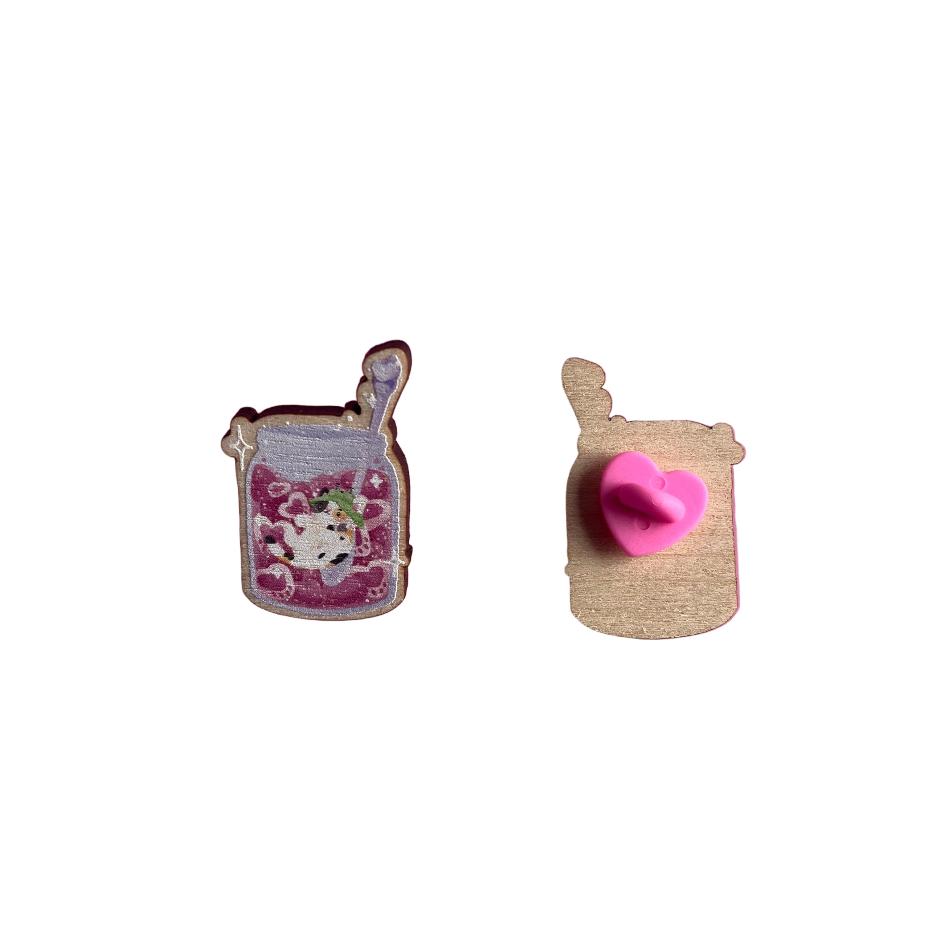 Wooden pin badge of a pawberry (heart-shaped strawberries with a paw shape inside) jam jar, with Bucket the calico cat inside. The spoon has a bee on it. This badge is printed onto 3mm thick responsibly sourced European birch plywood.