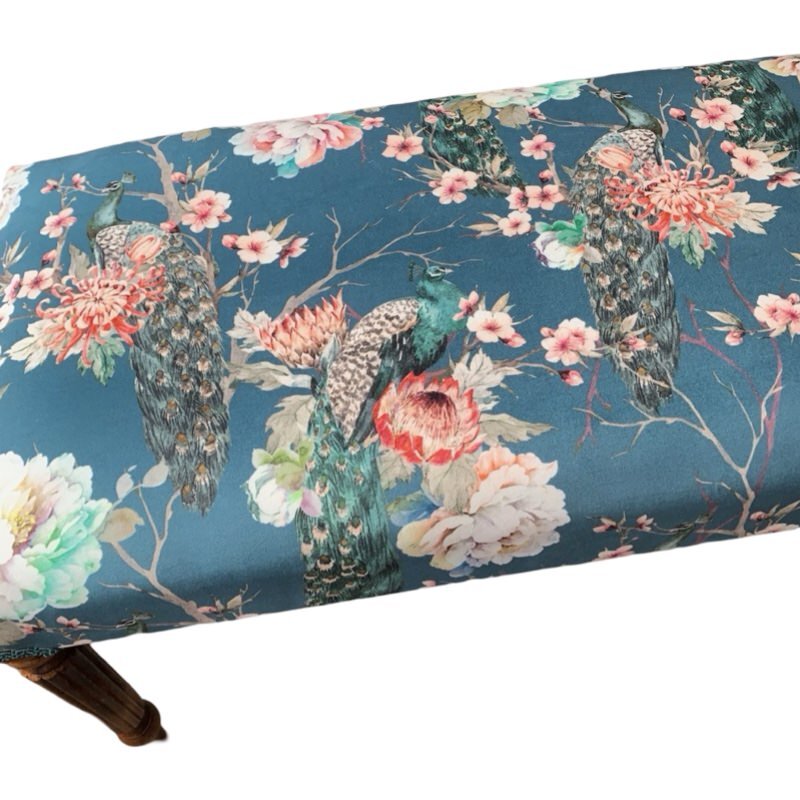 A hand-crafted rectangular bench covered in luxurious teal velvet with a floral pattern, featuring green peacocks and pink and white flowers, with teal binding and mahogany legs.
