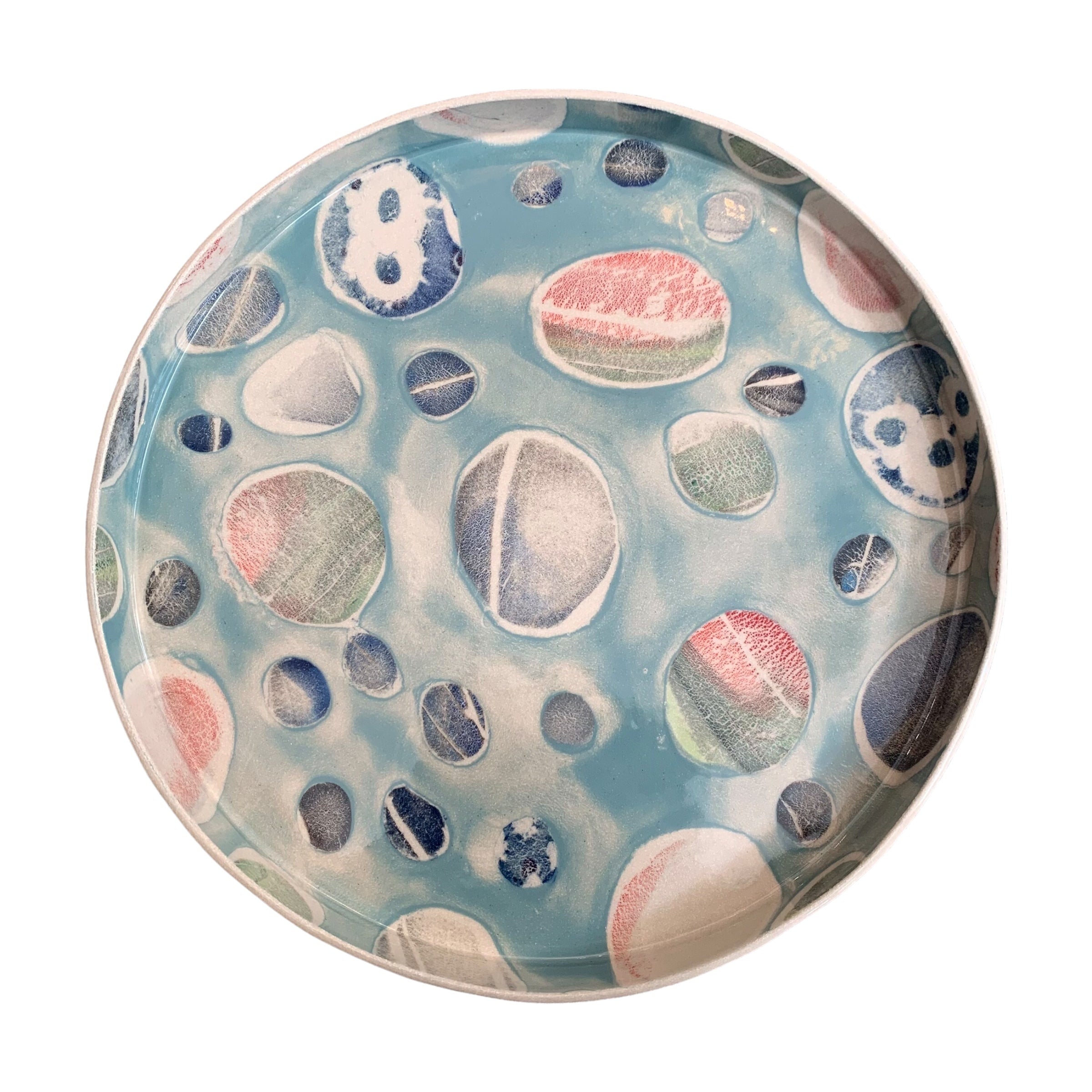 A ceramic platter in blue with a colourful pebbles design.