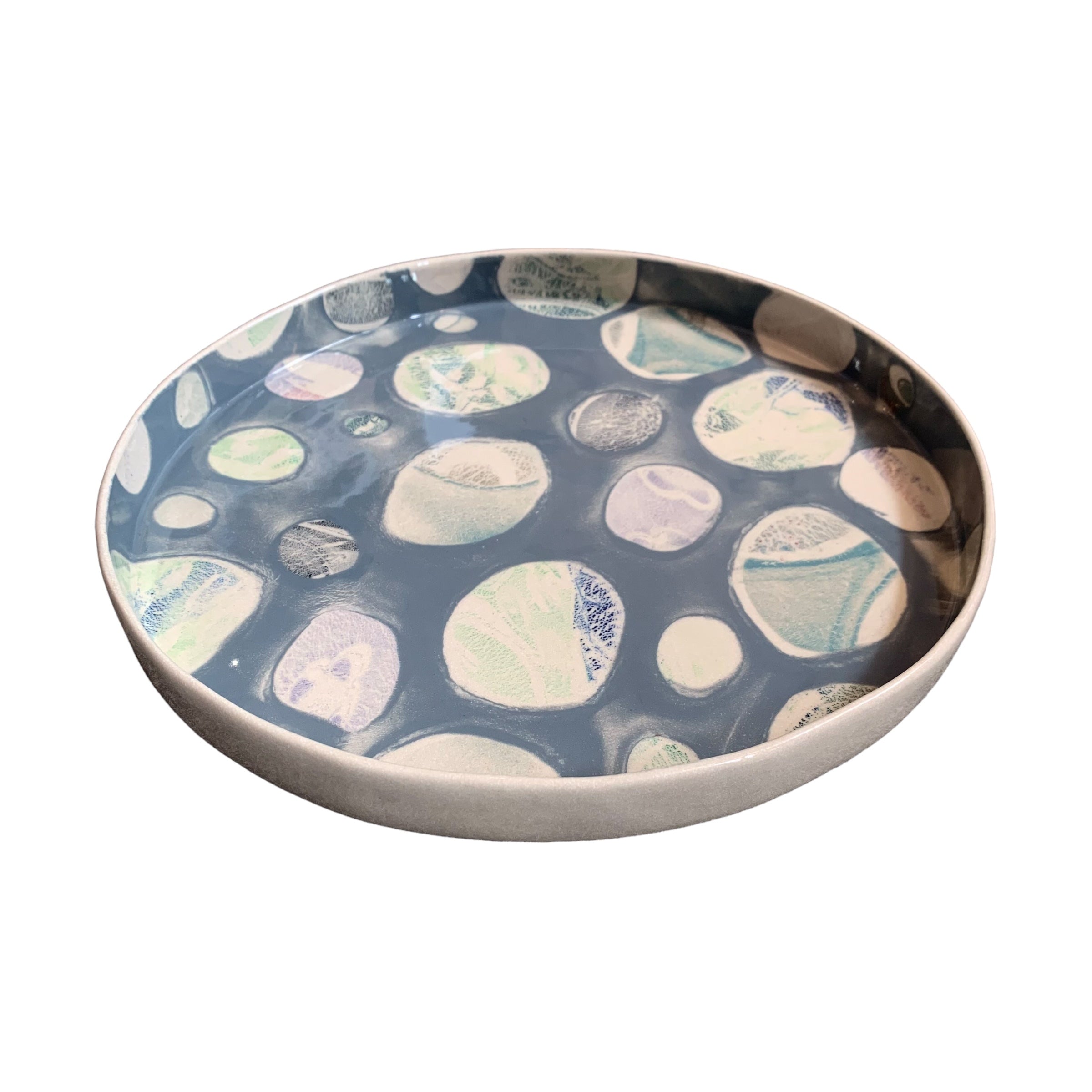 A ceramic platter in grey with a colourful pebbles design.