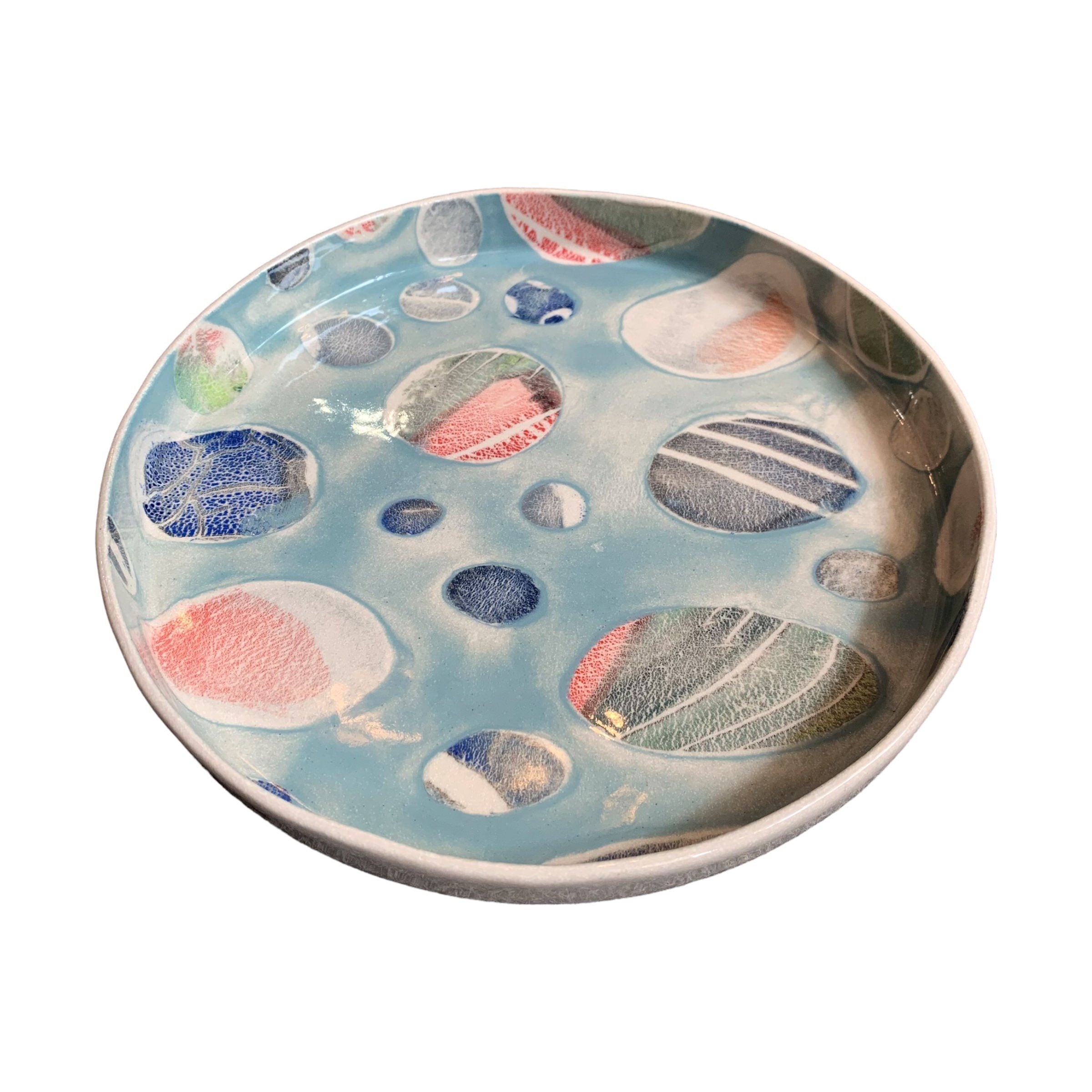 A ceramic platter in blue with a colourful pebbles design.