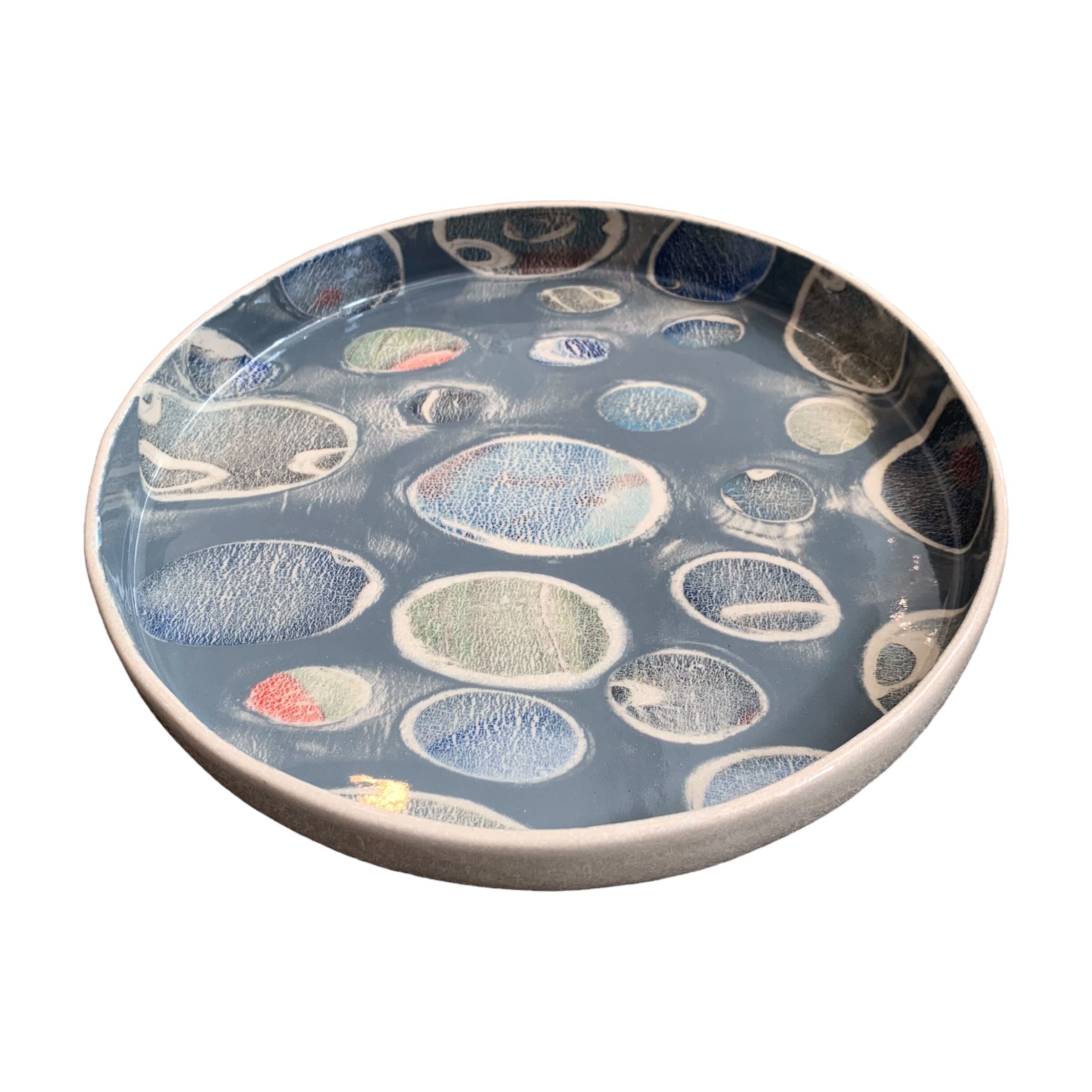 A ceramic platter in grey with a colourful pebbles design.