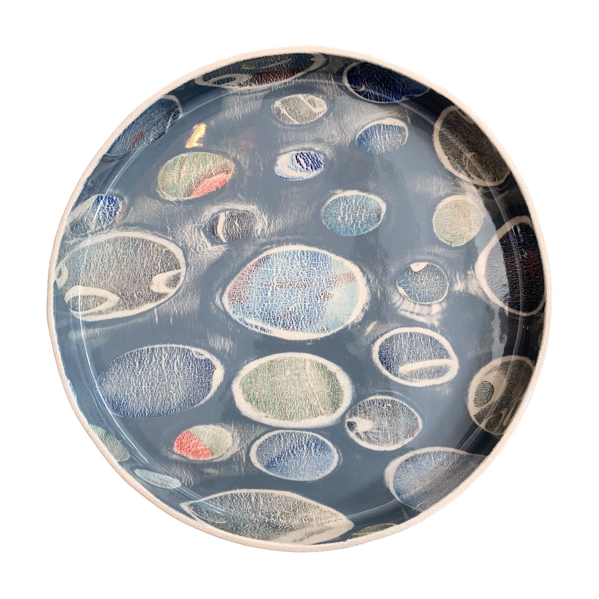A ceramic platter in grey with a colourful pebbles design.
