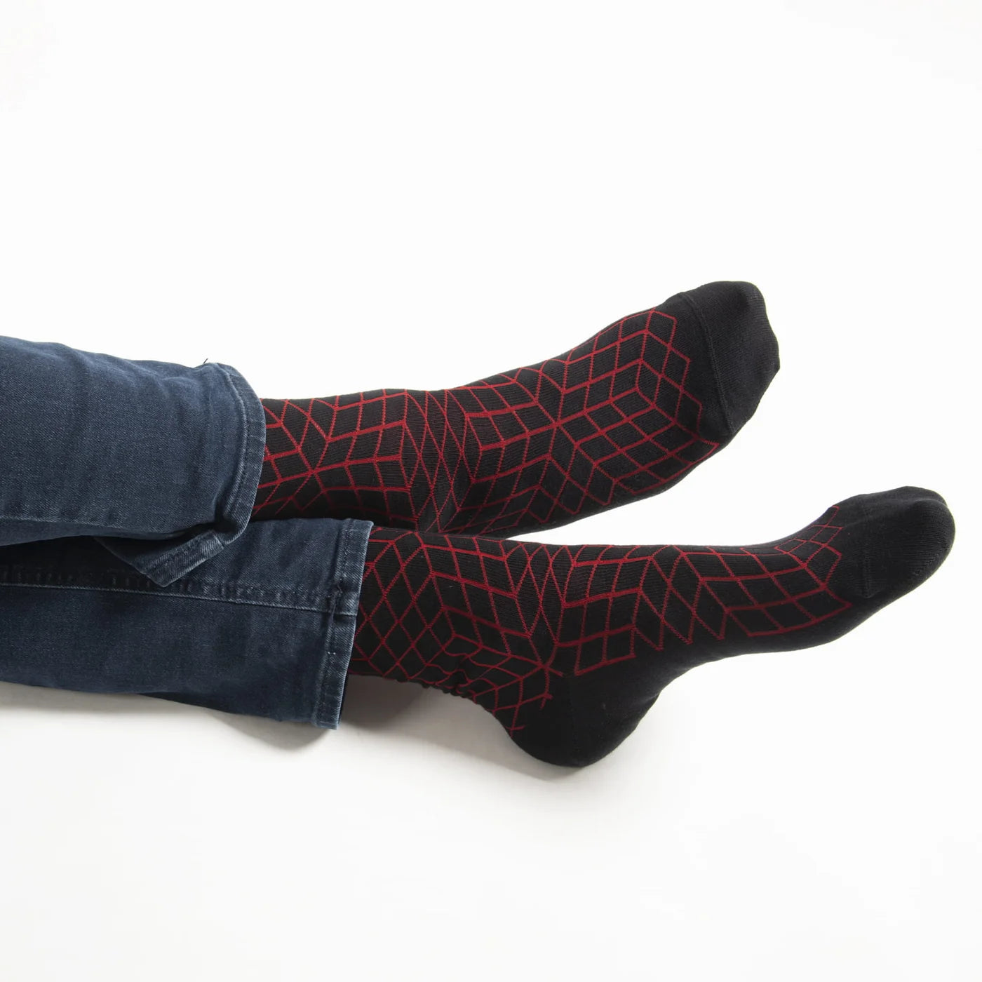Black socks with red geometric pattern worn by a person on a white background.