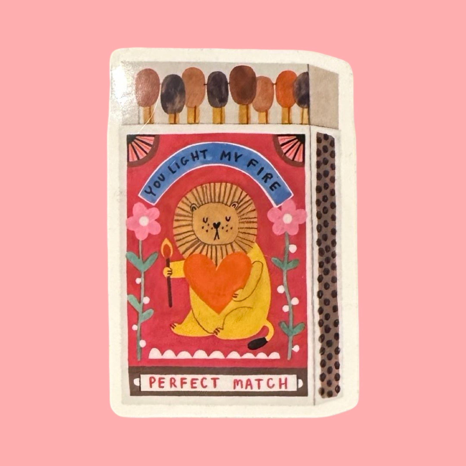 Matchbox with a lion illustration and text on a pink background.