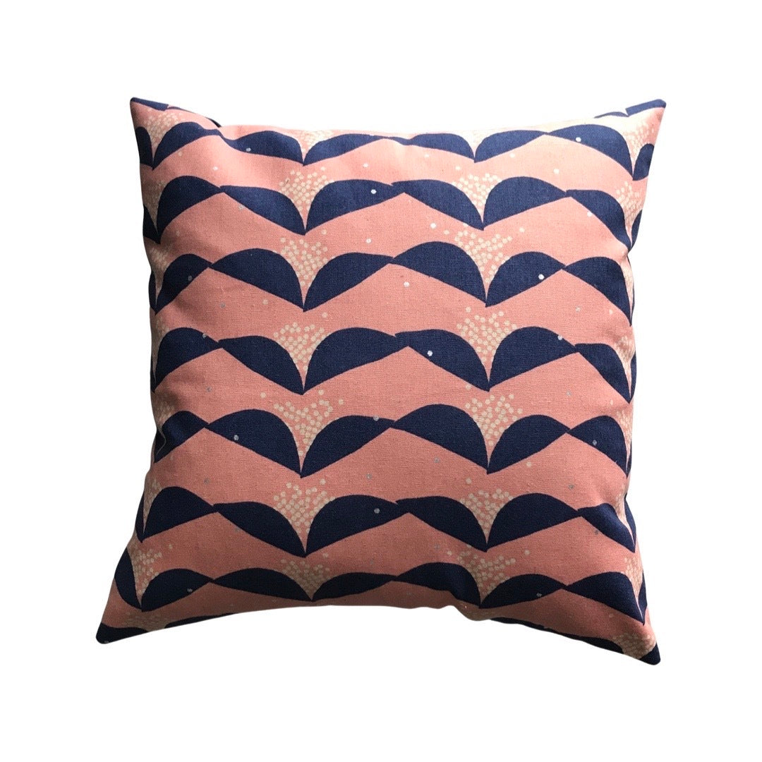 A cushion cover with a pink background and navy abstract floral pattern.