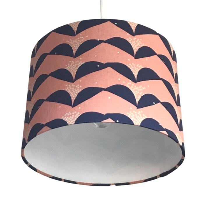 A cylindrical lampshade with a pink background and navy blue abstract floral pattern.