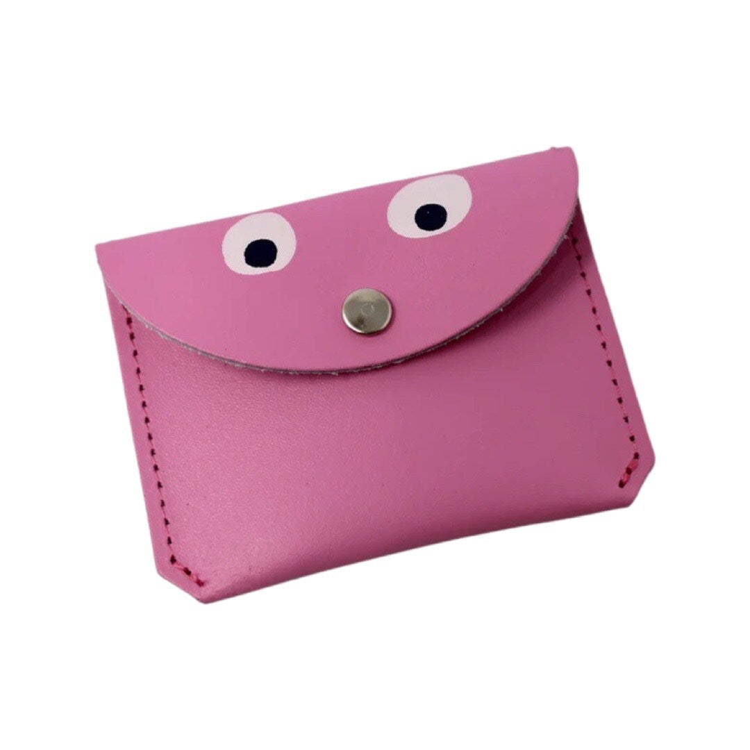 A pink leather coin purse with googly eyes and a gold fastening in the centre.