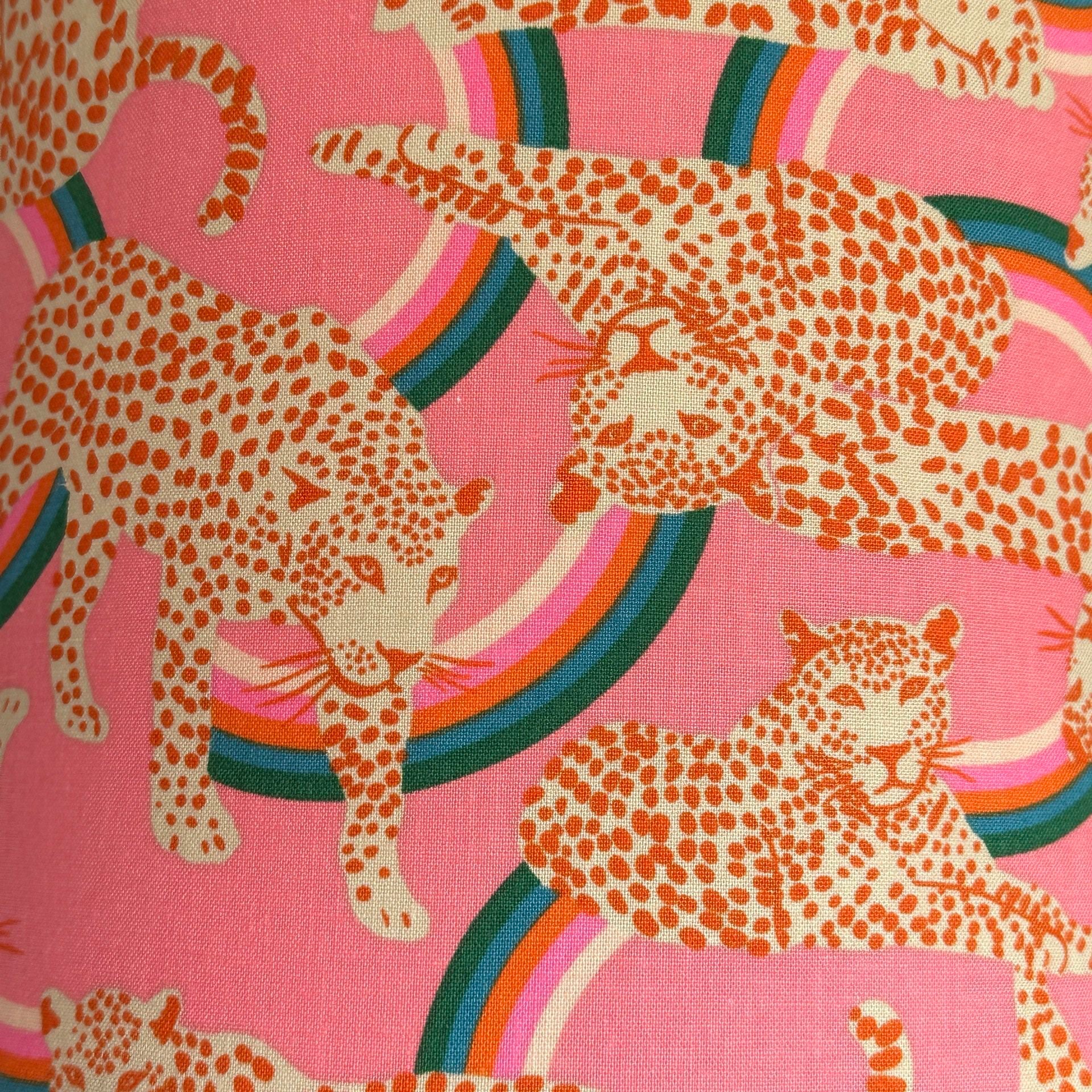 Fabric featuring red and white leopards on a pink background with green, blue, red, pink and white swirls.