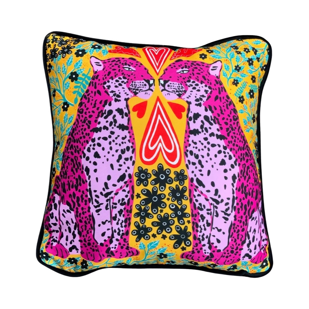Colourful cushion featuring two pink panthers, red love hearts and green and black flowers against a mustard background.