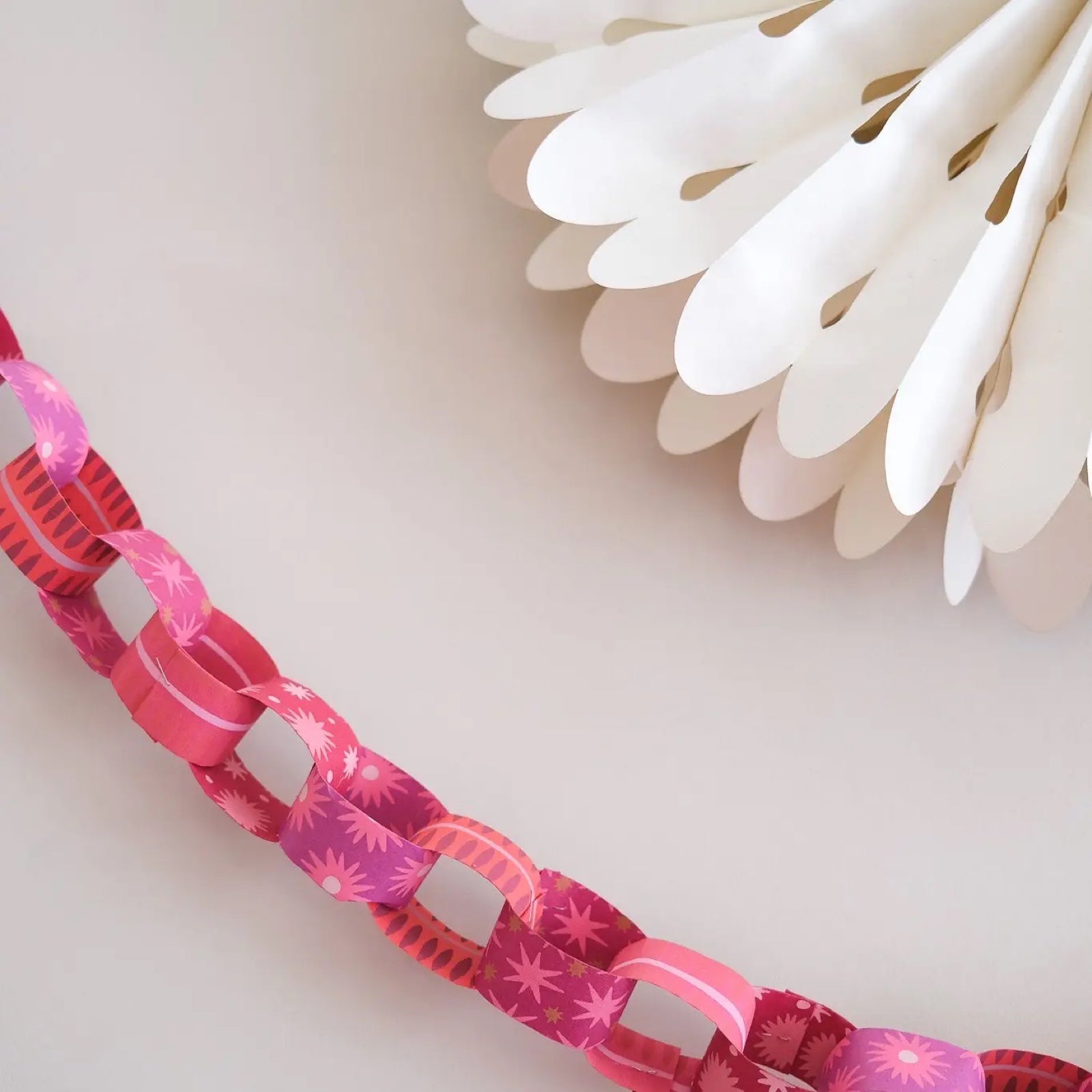 A paper chain made from pink paper with pink stars and ovals.