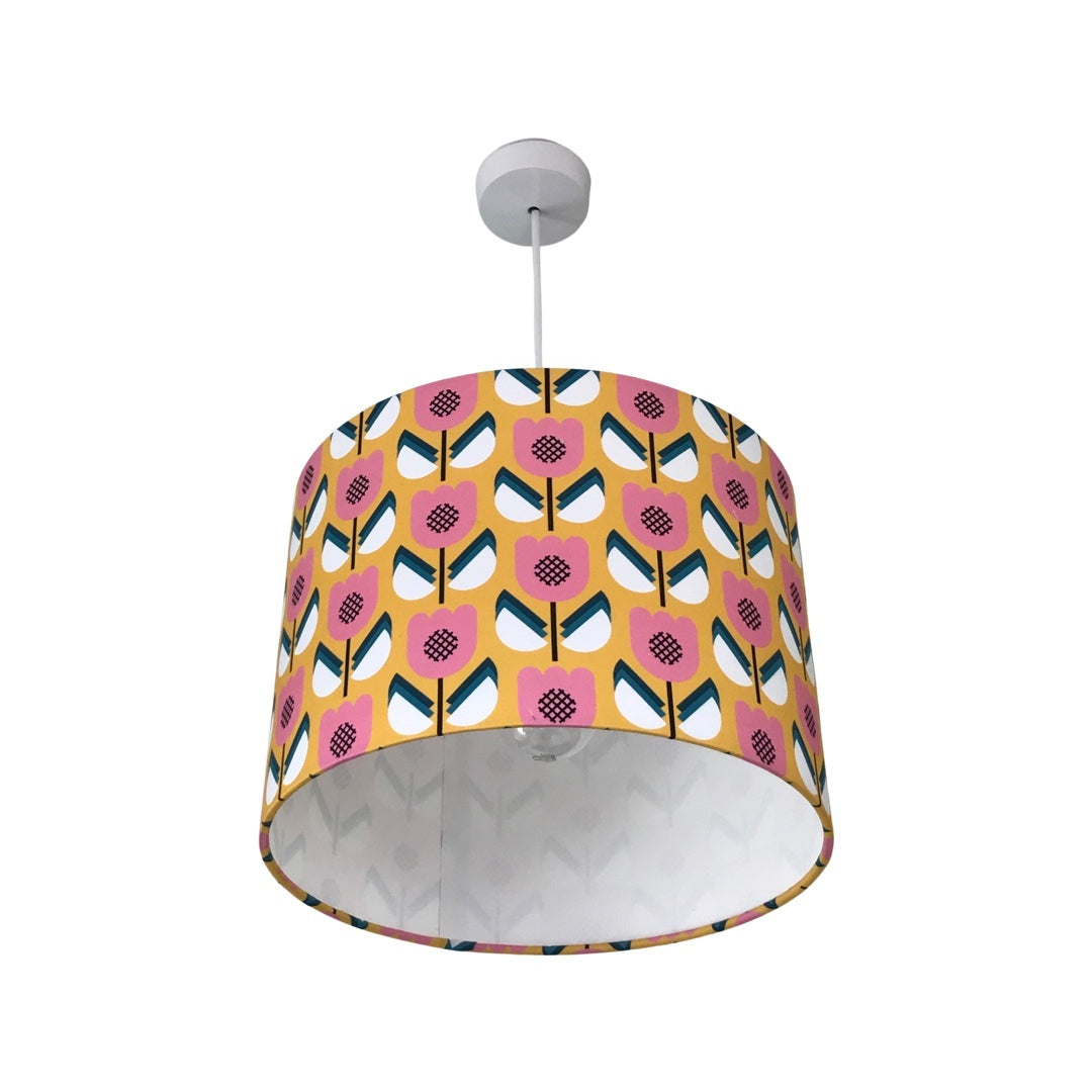 Drum lampshade covered in cotton retro-inspired fabric with a mustard background and pink, white and blue flowers.