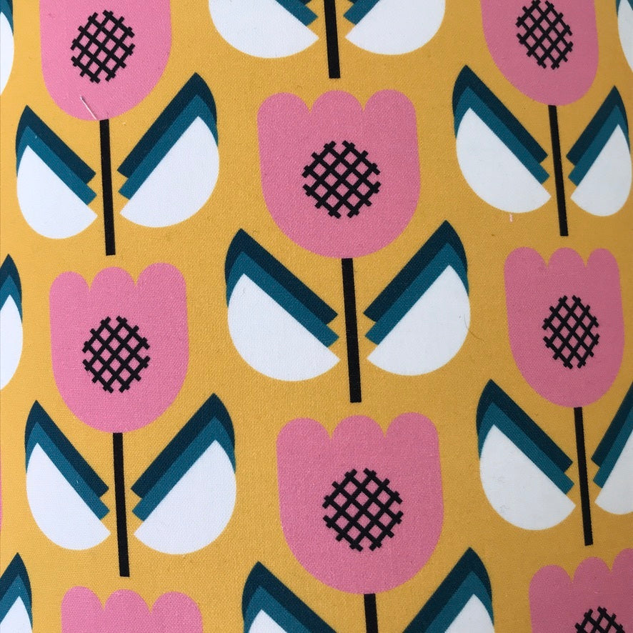 Cotton retro-inspired fabric with a mustard background and pink, white and blue flowers.