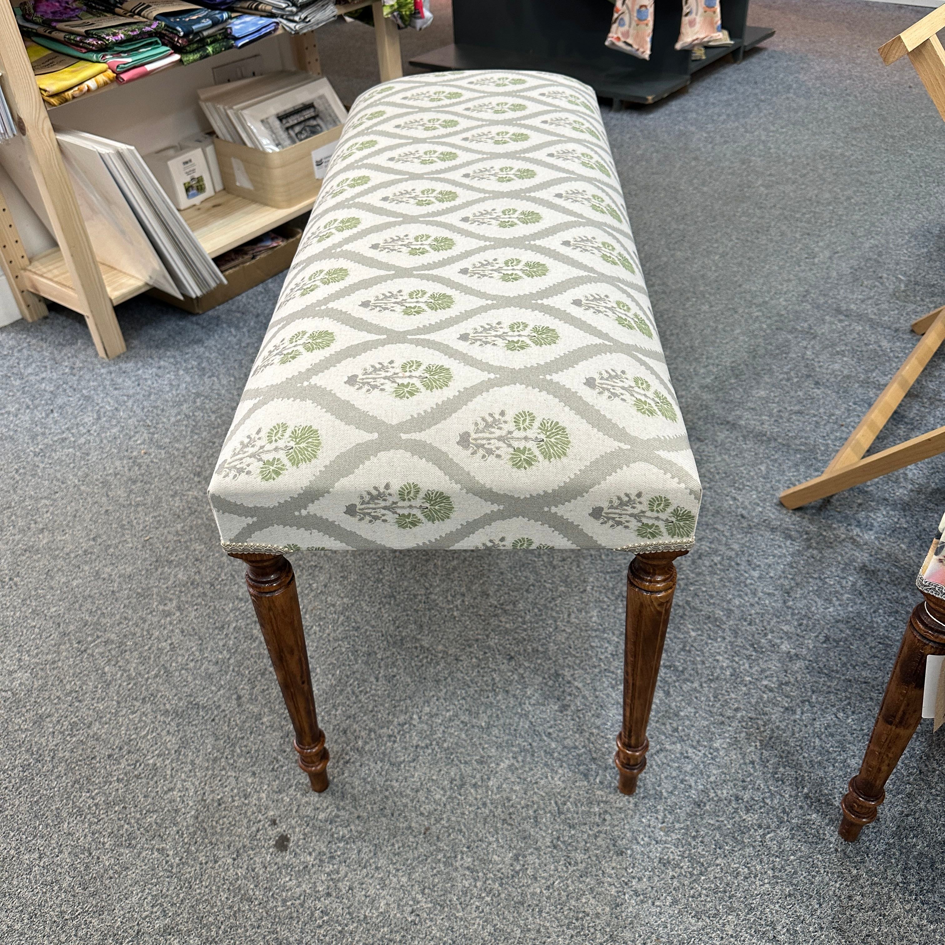 Fabric-covered bench with patterned top on a grey floor.