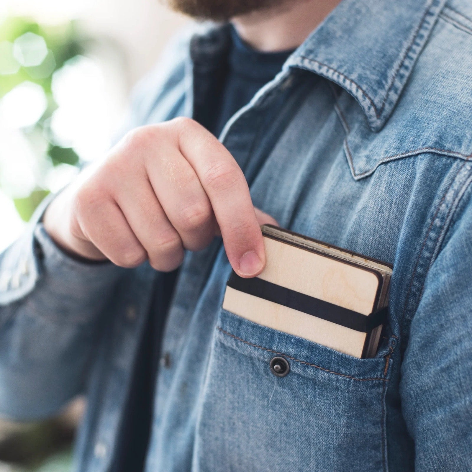 Person wearing a denim jacket with a flower press in their pocket.