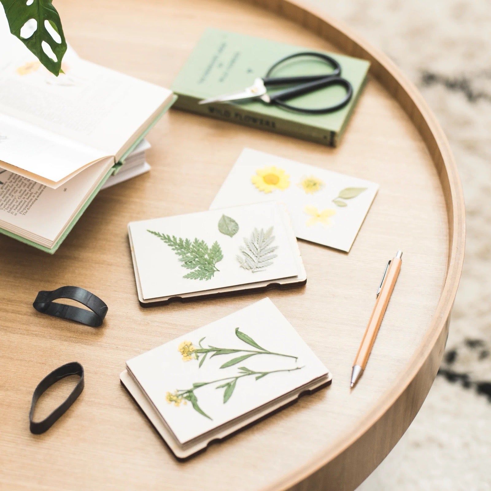 Notebooks with pressed flowers and leaves on a wooden table.